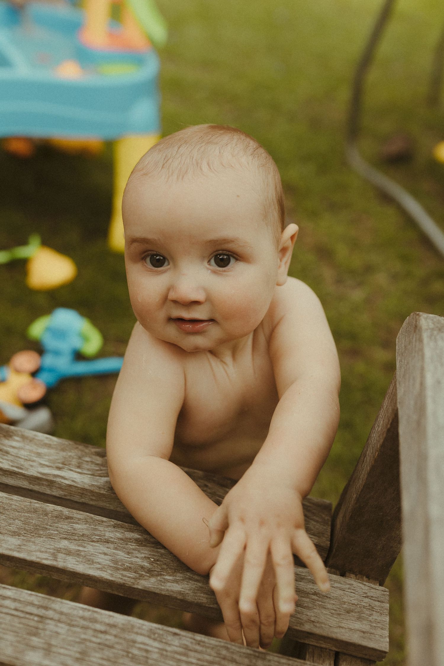 Close-up sequence of a baby peering over a wooden bench outdoors with curious expressions.