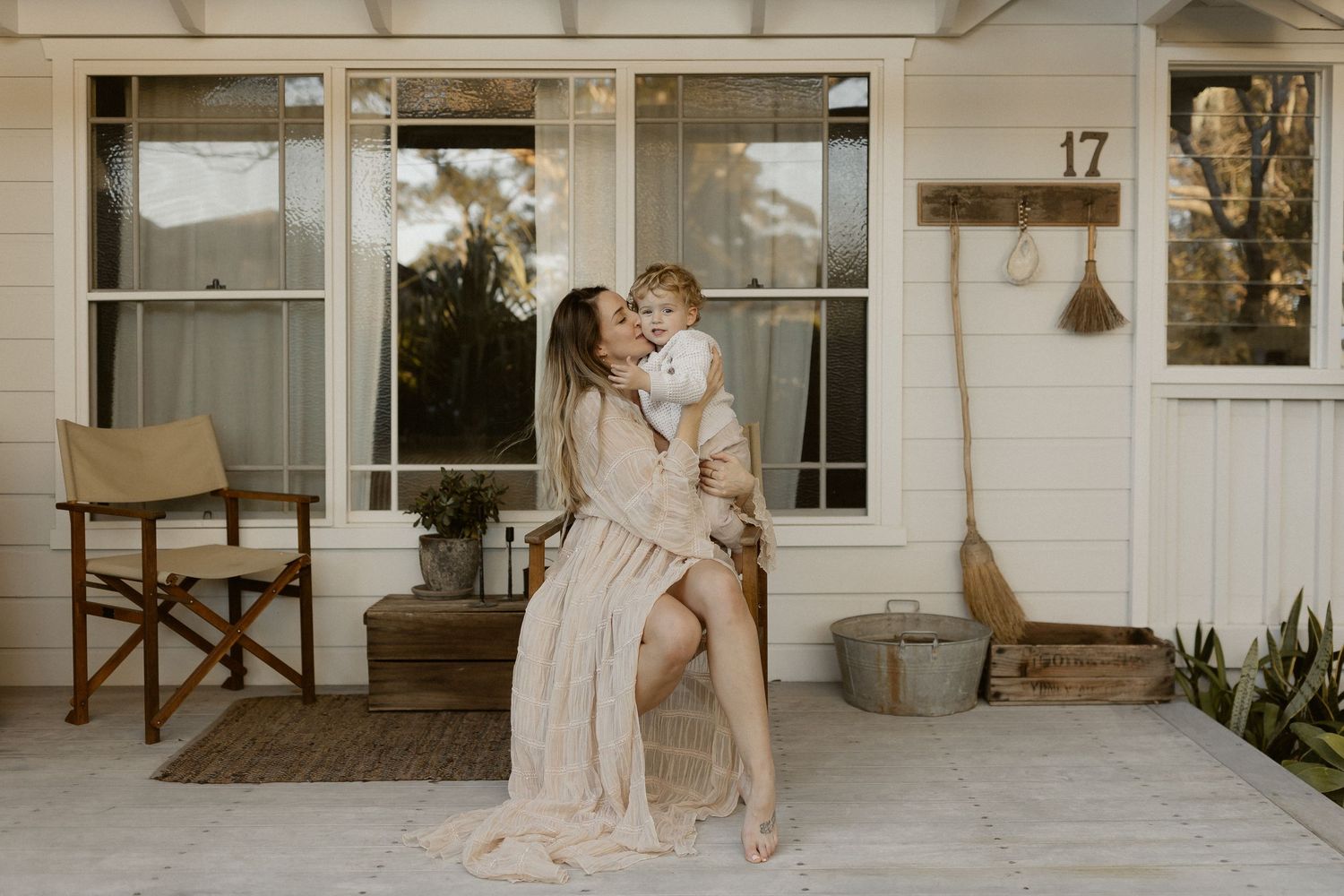 Romantic couple embracing on front porch of white house number 17 at sunset.