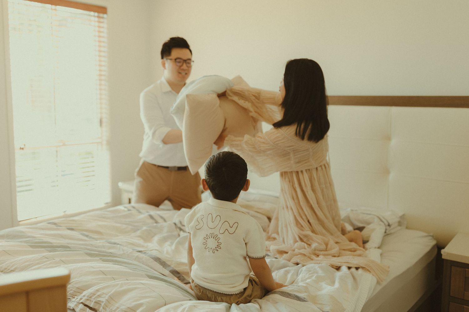 Family members share joyful moments together on a sunlit bed.