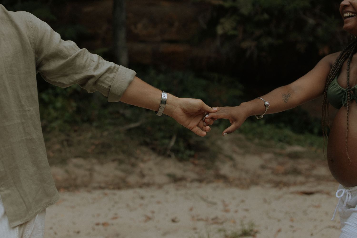 Two people holding hands in a romantic outdoor setting during sunset.
