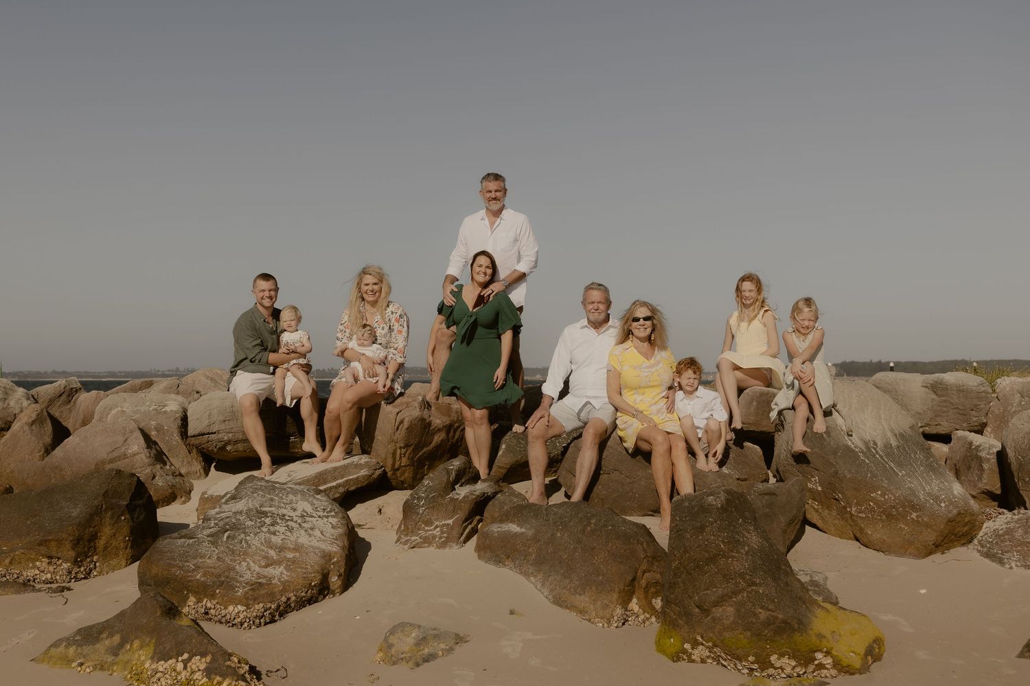 Group gathered on coastal rocks during golden hour at the beach for a casual outdoor photo session.