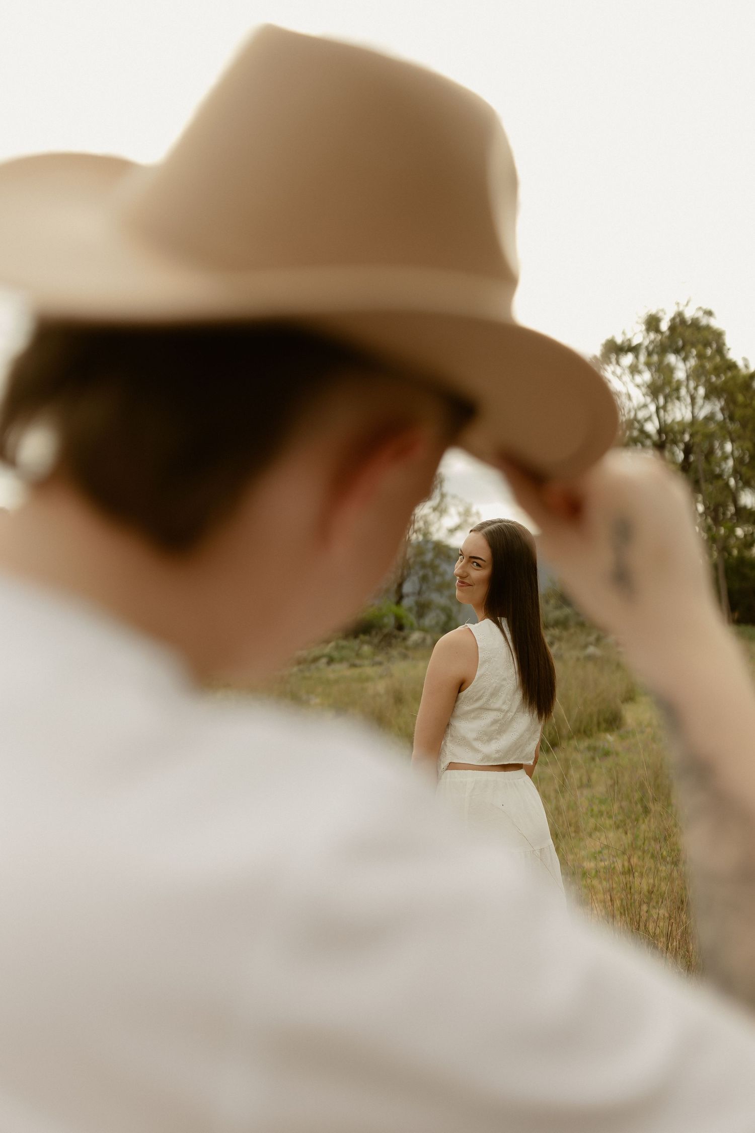 Soft focus artistic portraits taken through a cowboy hat in an outdoor setting.