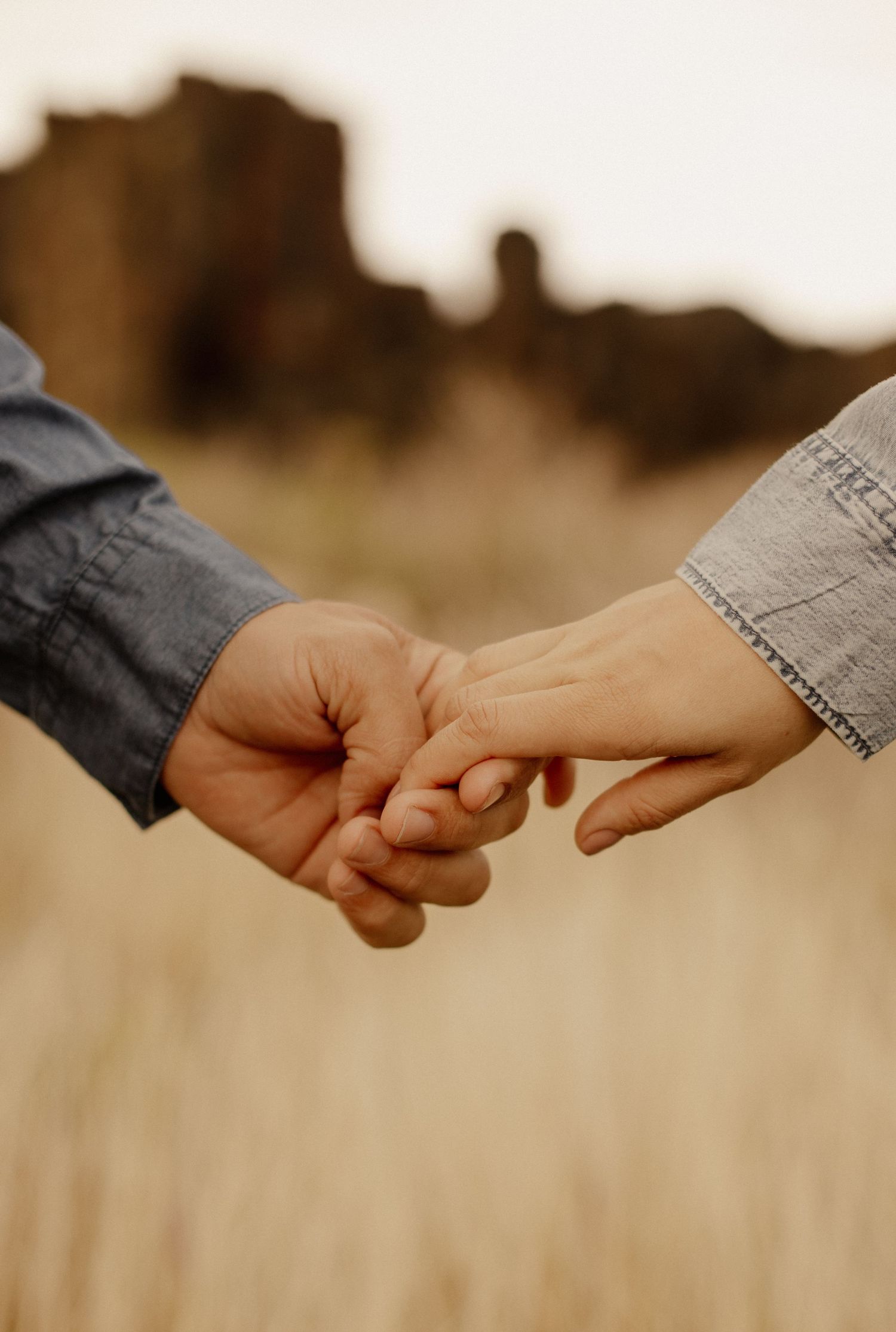 Two hands reaching out to each other in a warm sepia-toned photo symbolizing connection and togetherness.