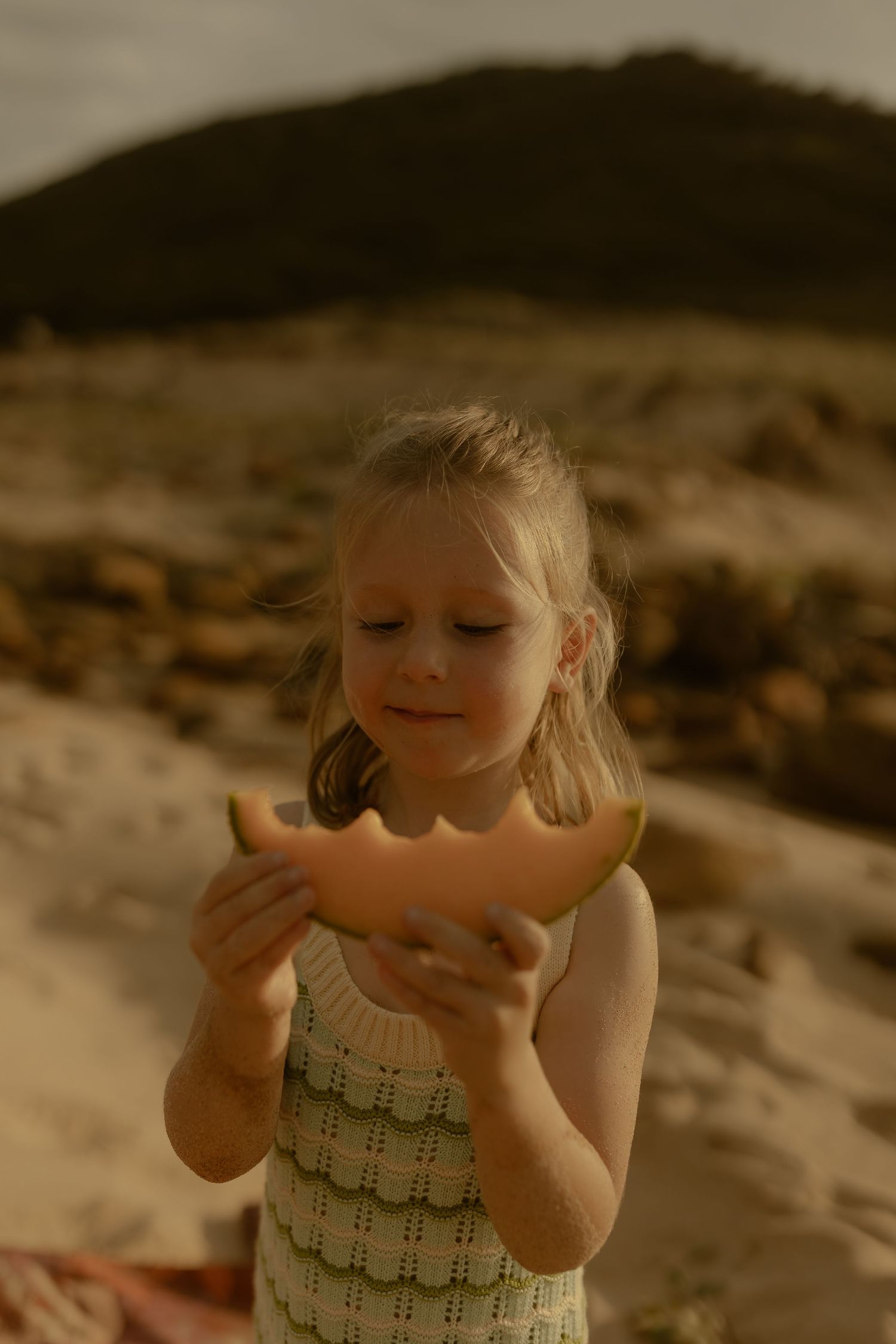 A child in a patterned swimsuit plays joyfully at the beach.