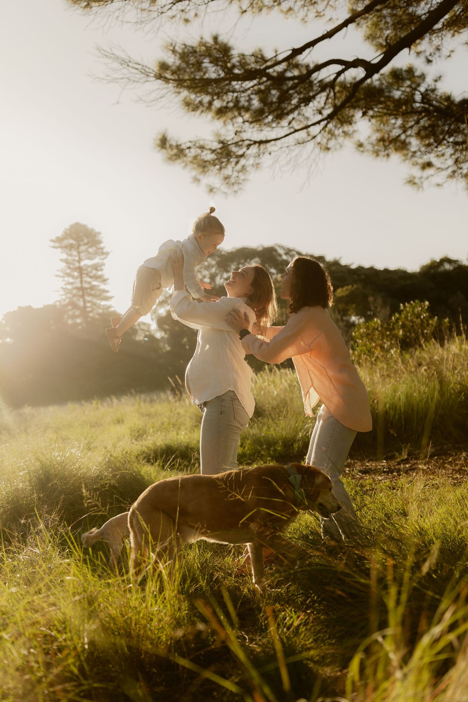A playful couple dances and spins together in a sunlit meadow during golden hour.