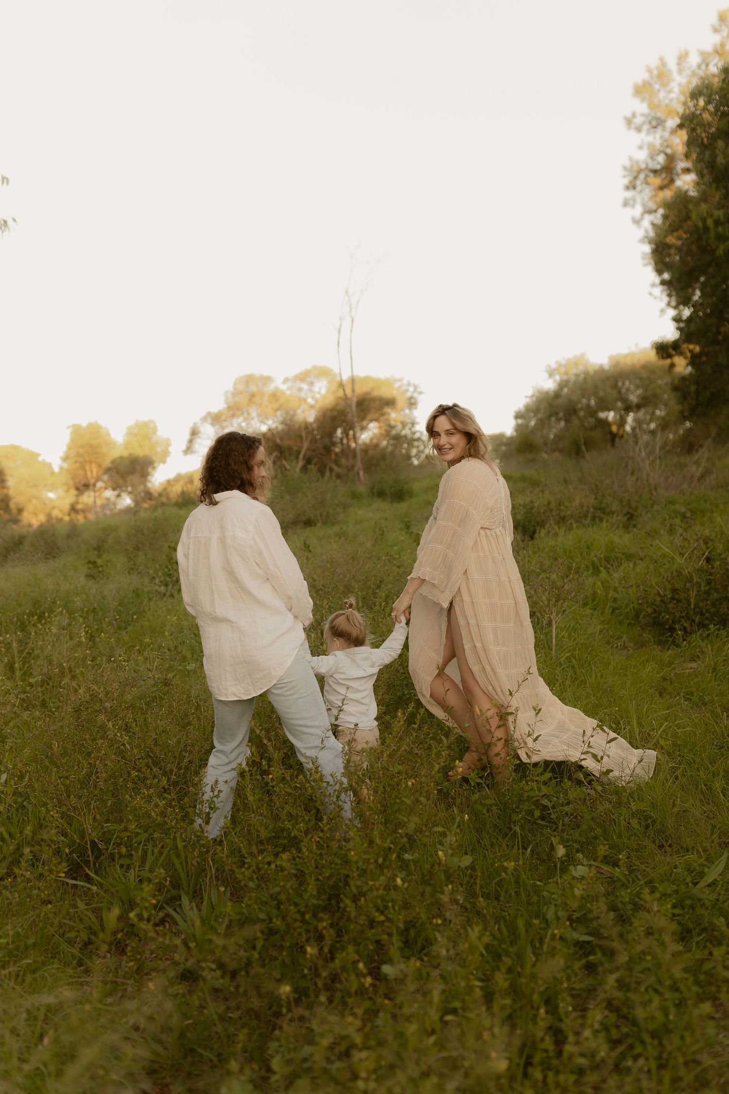 People sitting together in a grassy meadow during golden hour creating a dreamy, ethereal atmosphere.