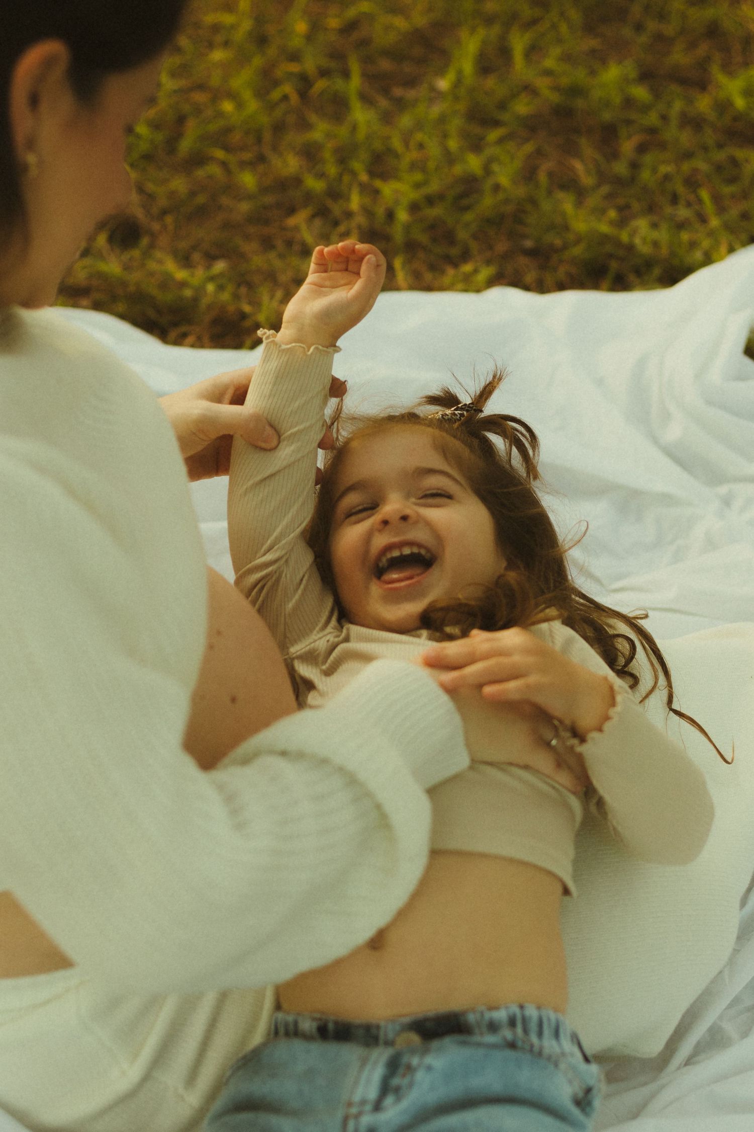 Playful moment on a white blanket outdoors filled with joy and laughter.