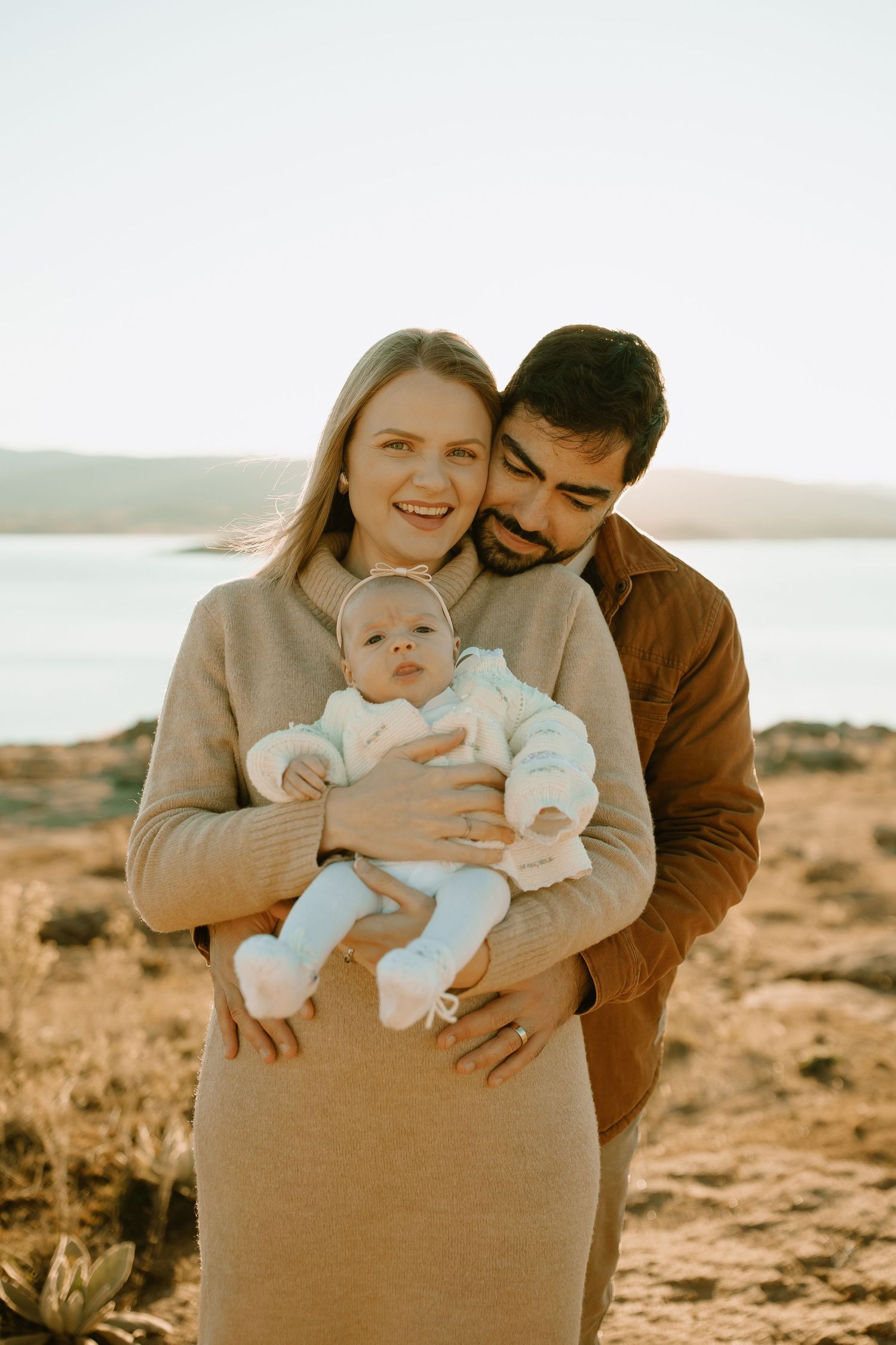 Beautiful family portrait taken at sunset by a scenic lake with desert landscapes in the background.