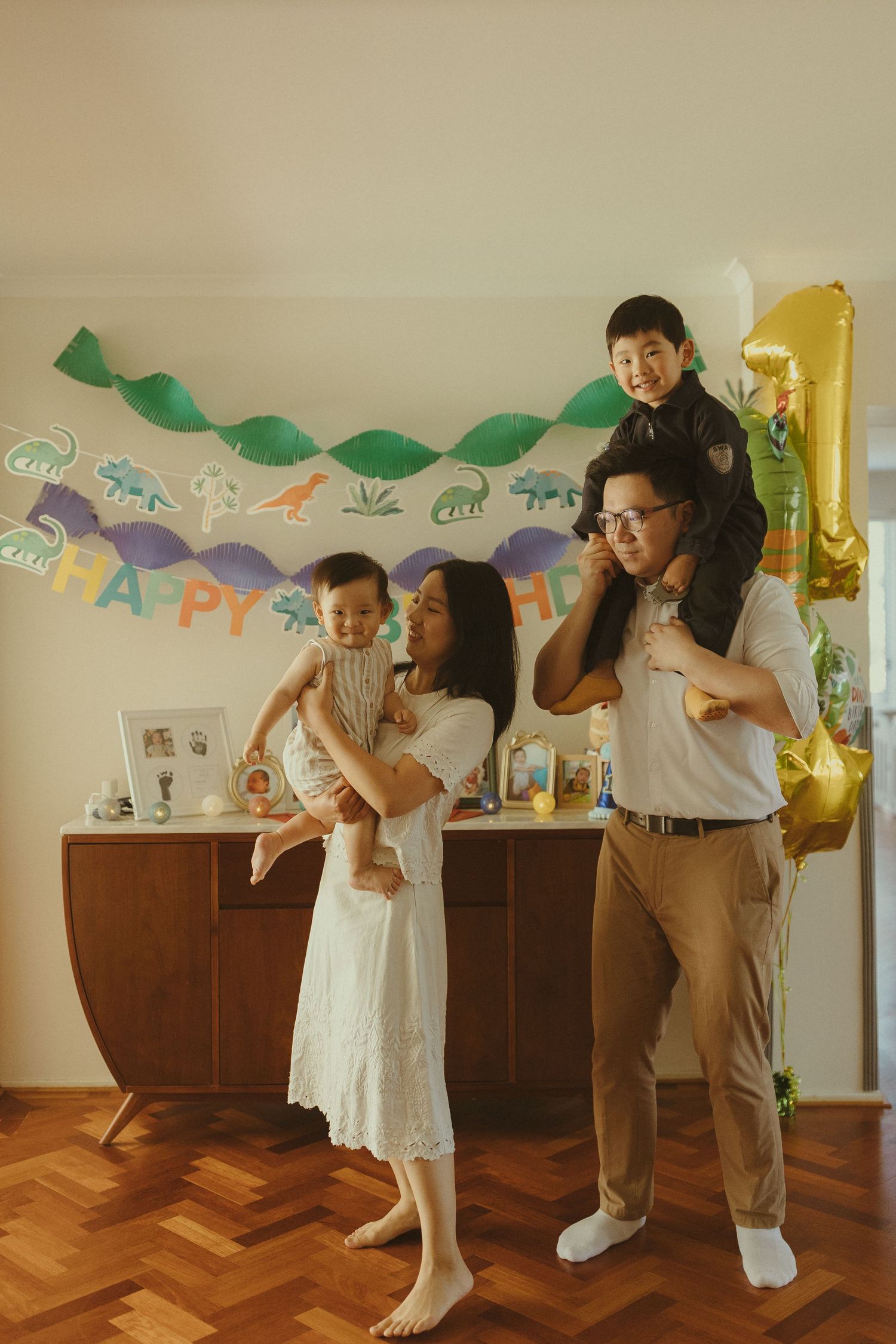 A family celebrates with joyful dancing under birthday decorations.