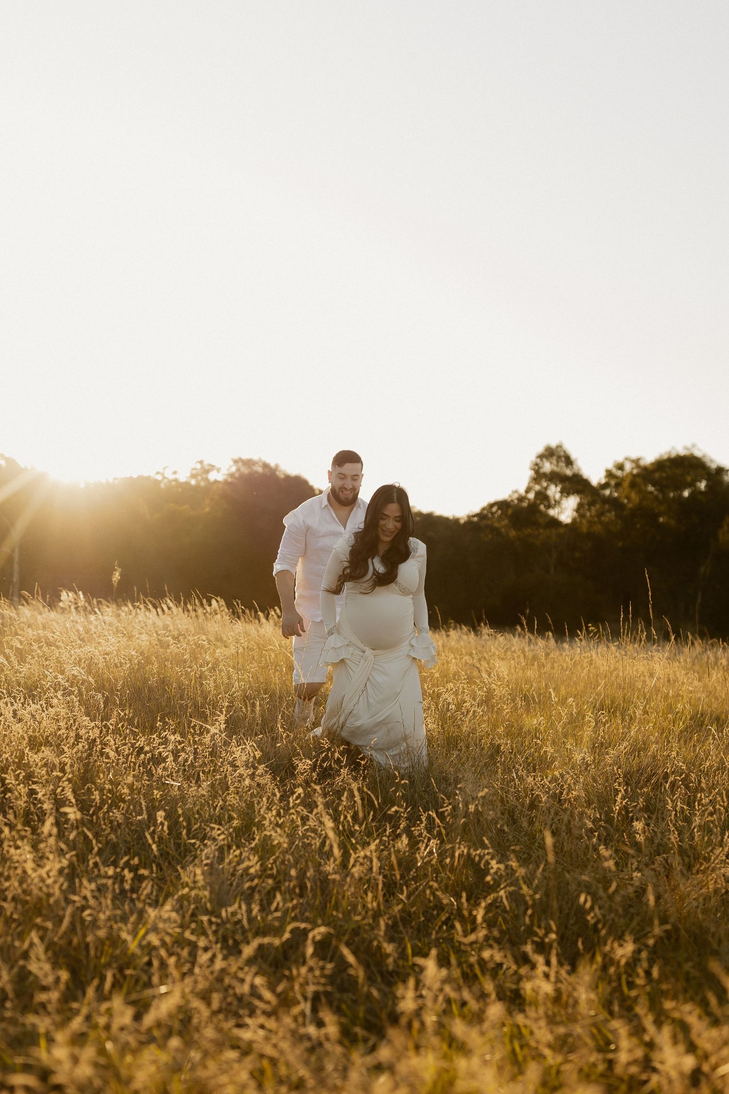 Romantic couple embraces in a sun-drenched golden field during sunset creating a dreamy silhouette.