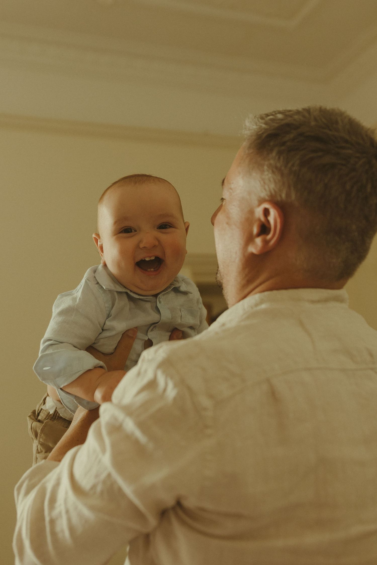 A series of heartwarming moments showing a baby laughing and playing while being held in a white shirt.