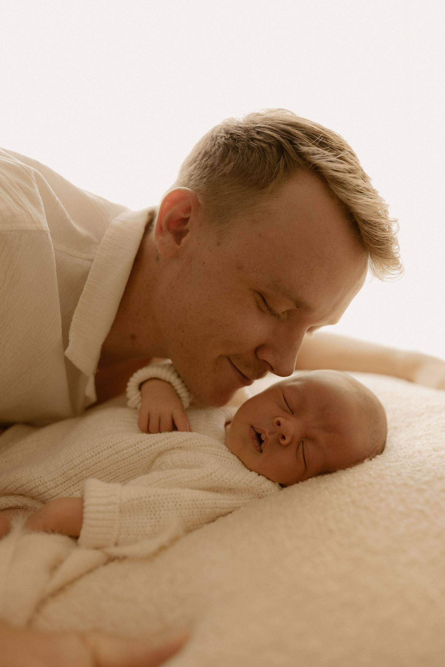 Warm toned intimate portrait of tender parental moment with sleeping newborn.