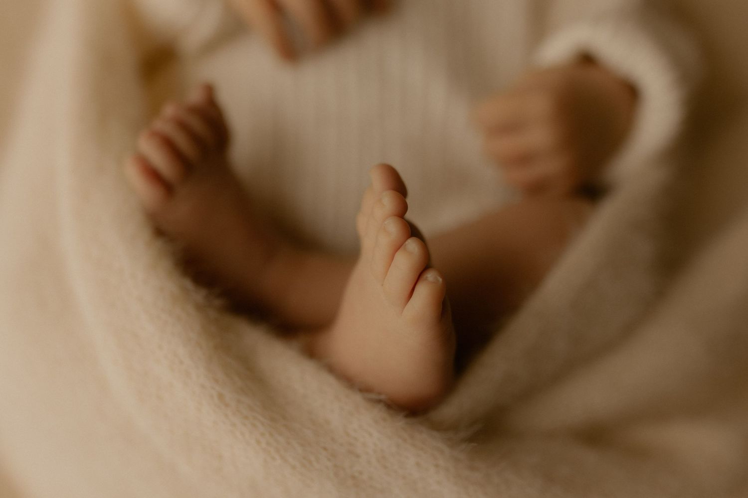 A close-up shot of a newborn baby's tiny feet against a soft beige background.