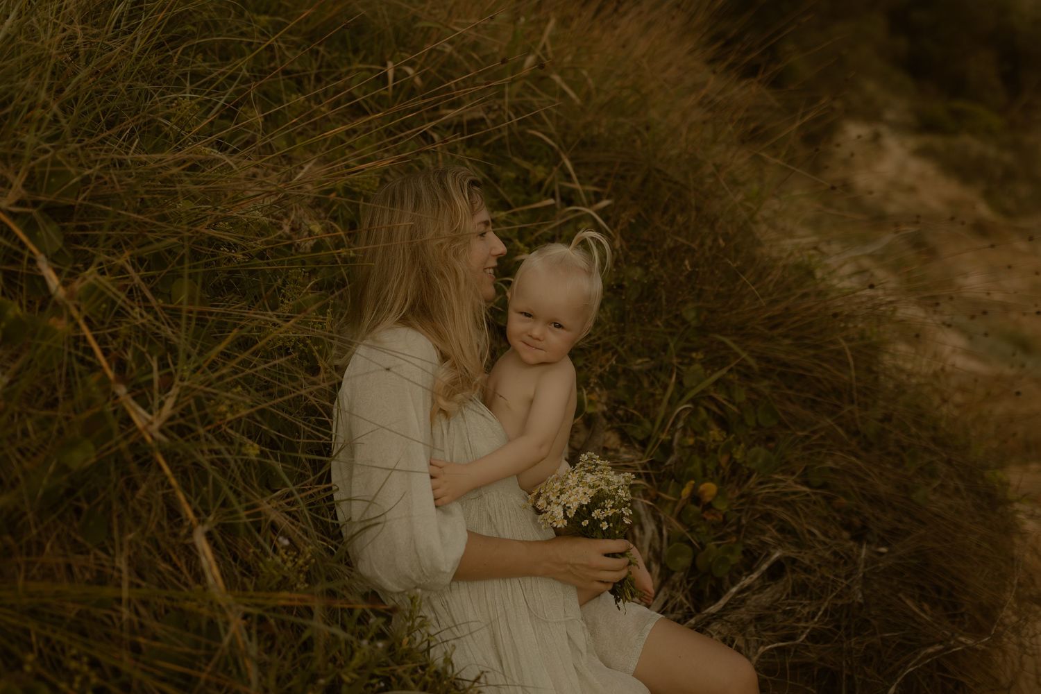 Intimate family embrace captured in warm tones against natural coastal backdrop.