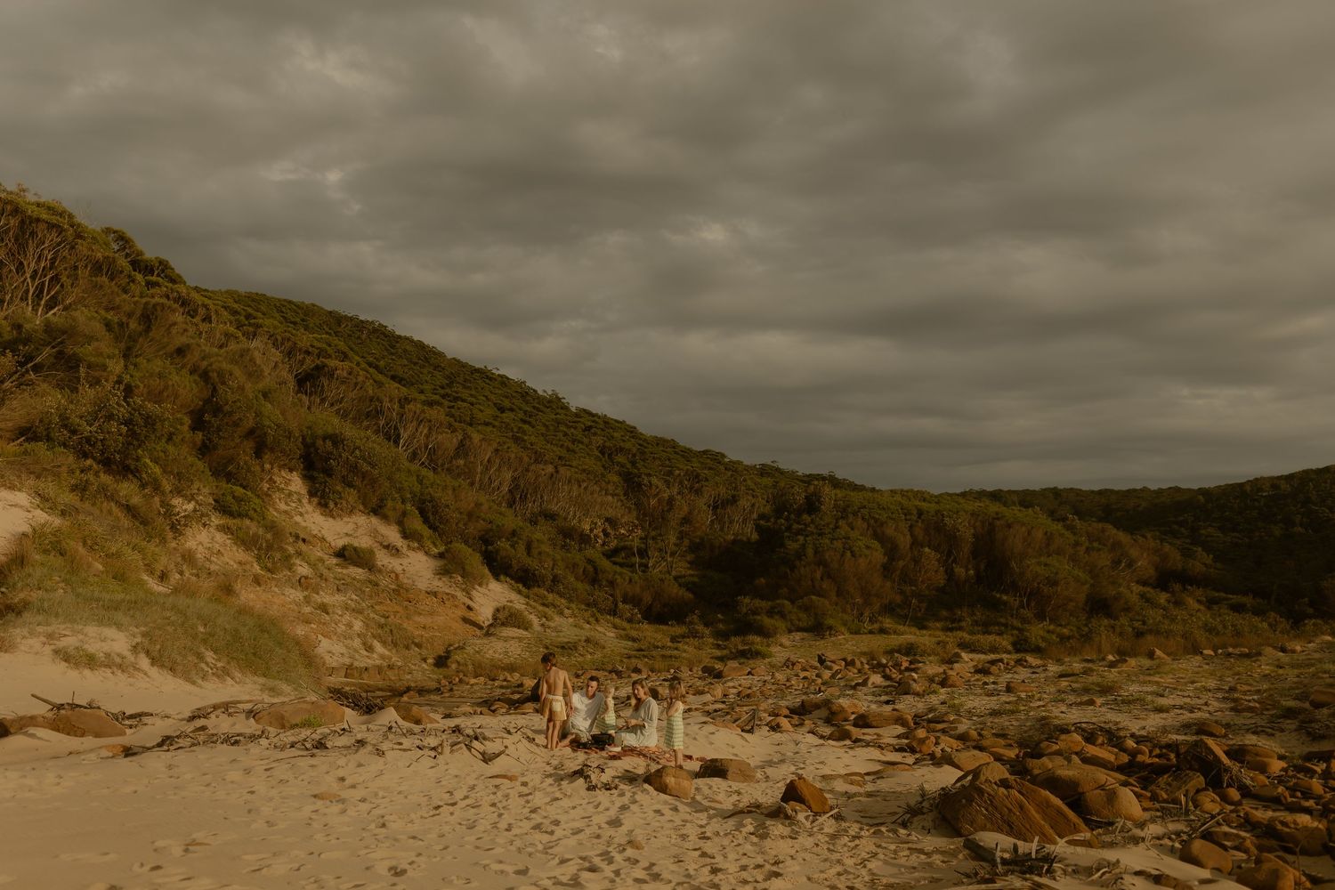 A panoramic view of coastal cliffs and sand dunes under cloudy skies.