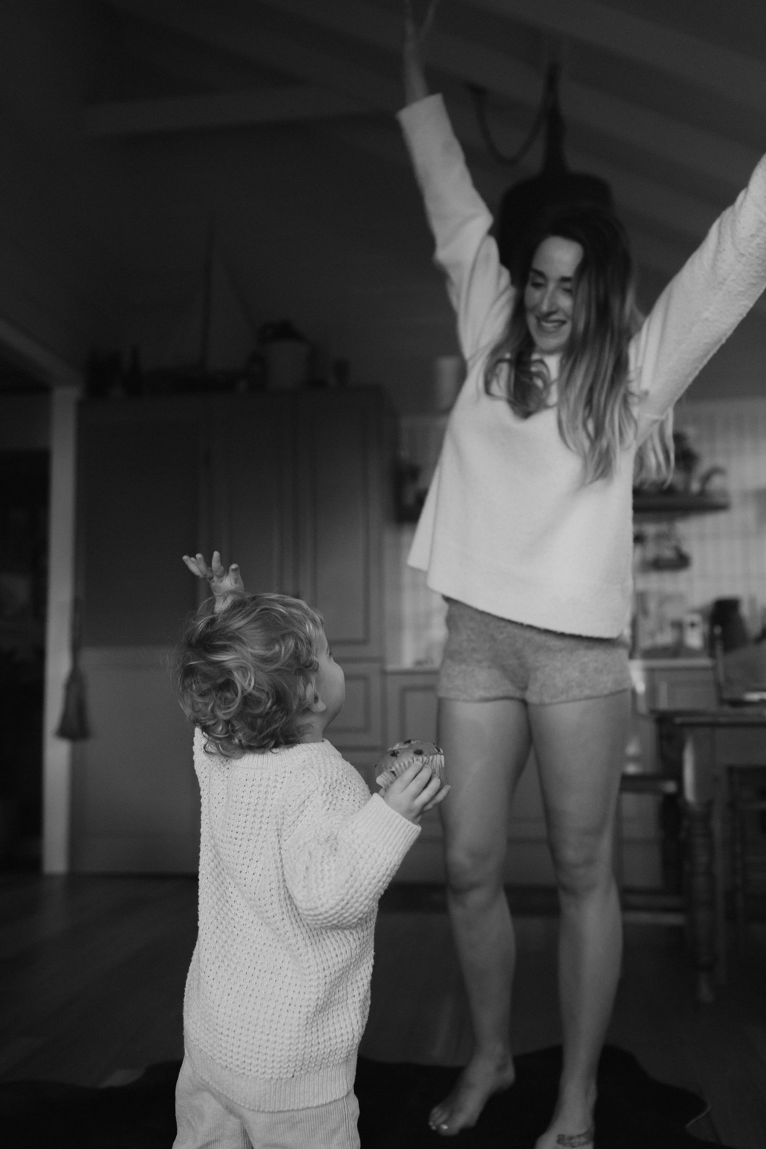 A black and white photo of joyful dancing in a home kitchen.