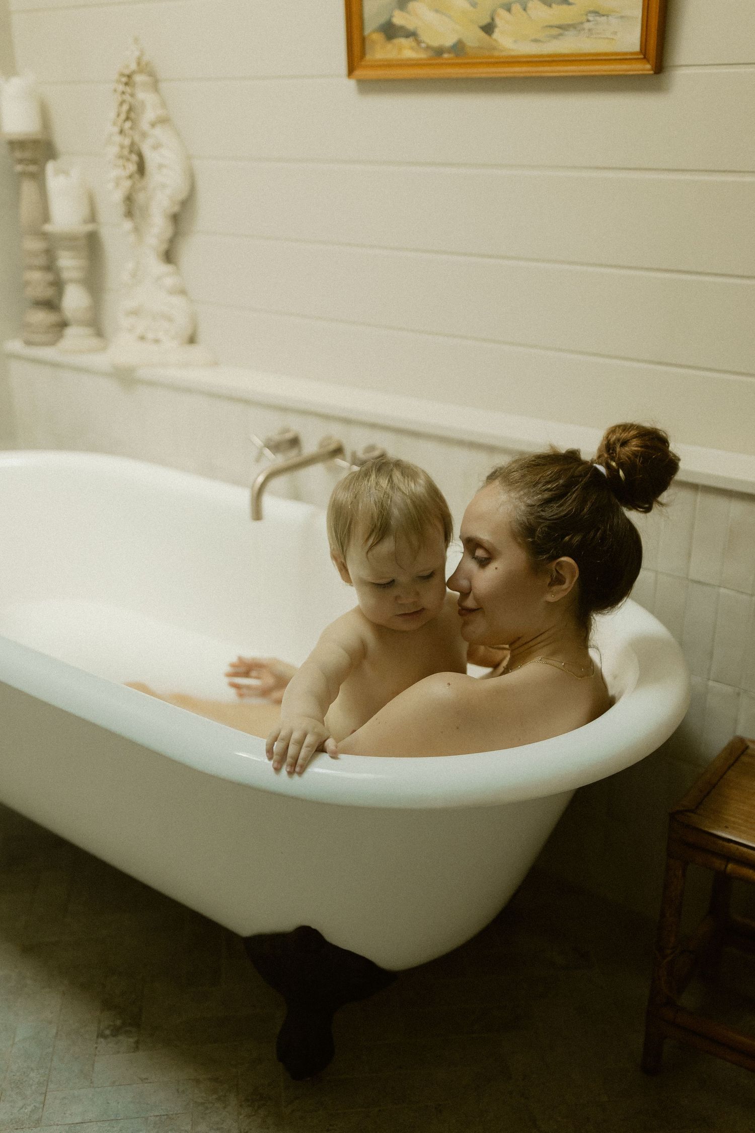 A pair of people relax and laugh together while lounging in a vintage white clawfoot bathtub.