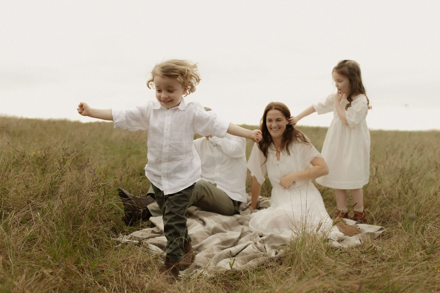 A family shares a joyful moment together on a blanket in a scenic meadow.
