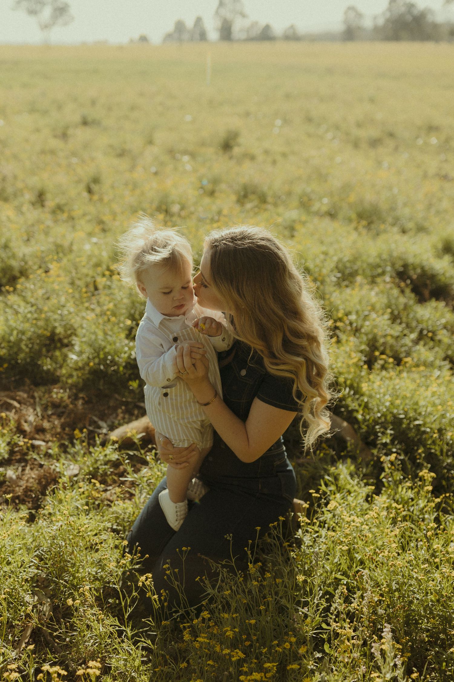A tender moment between parent and child in a wildflower meadow at sunset.