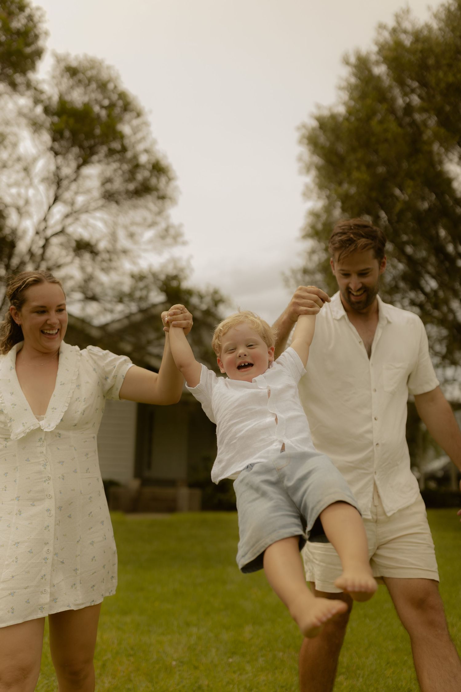Joyful family moment captured as they swing and play together in white outfits.