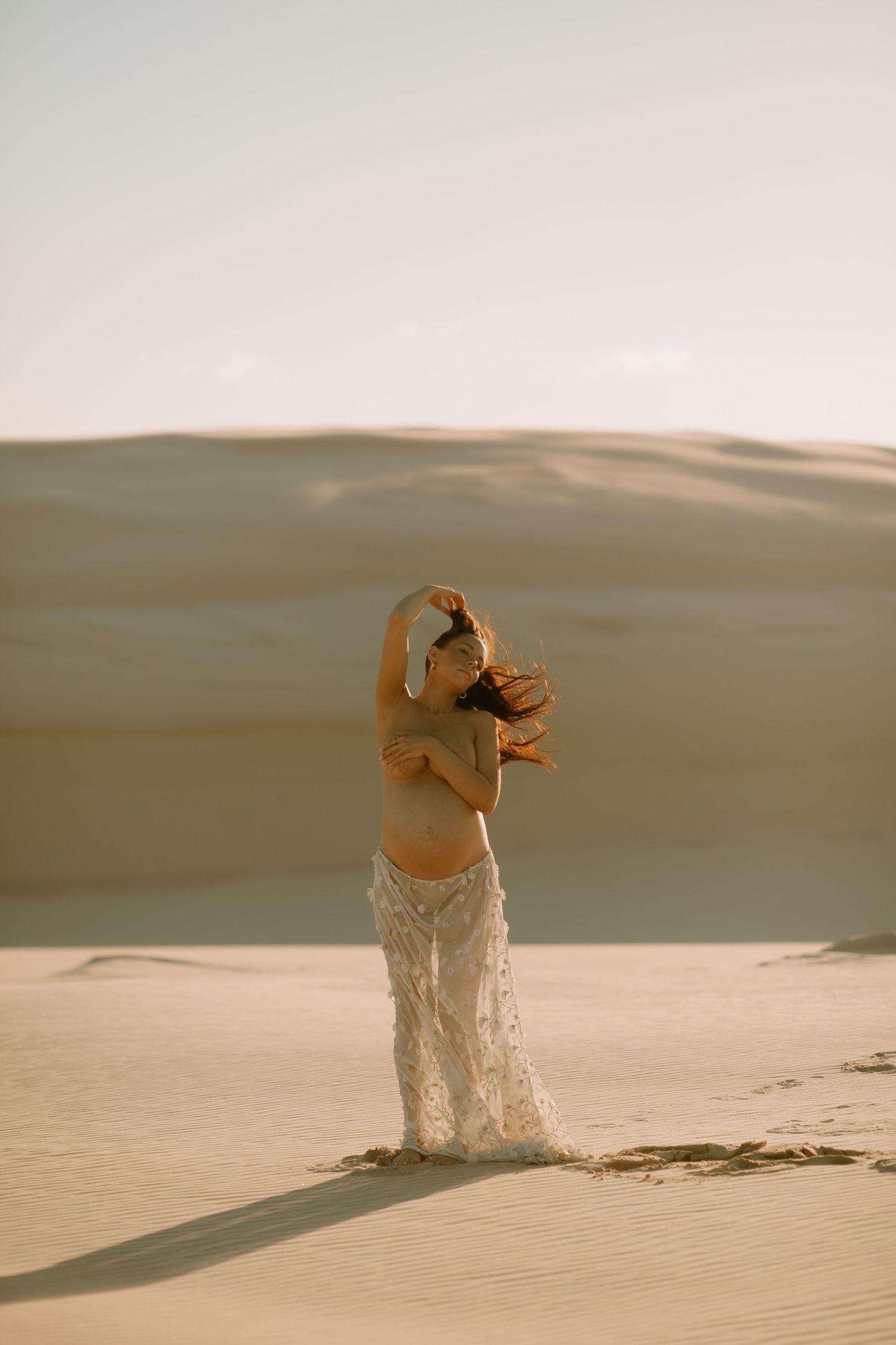 A series of images showing a person emerging from desert sand dunes at sunset, creating a surreal and artistic scene.