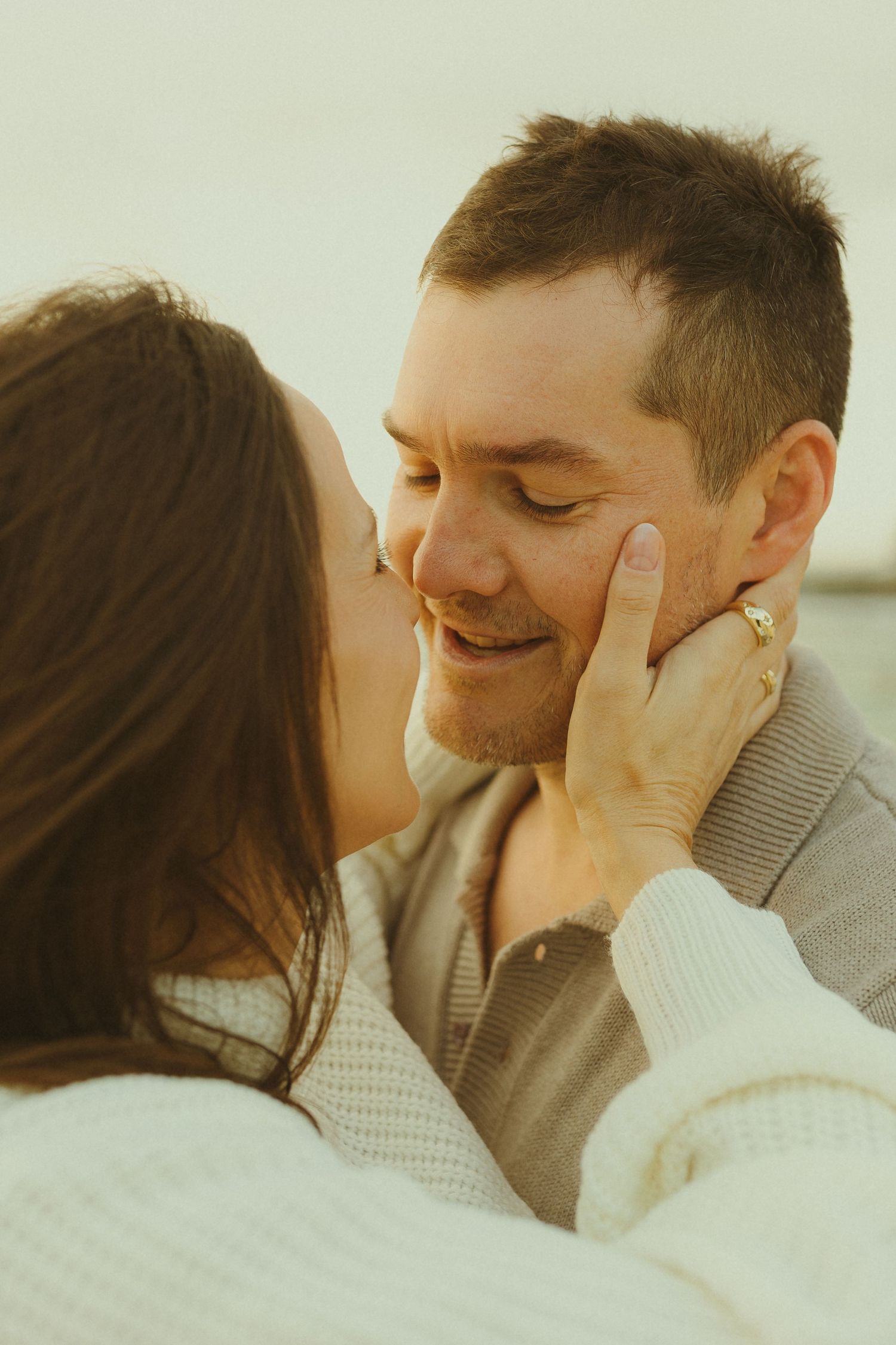 Close-up of tender moment between couple during beachside maternity photography session.
