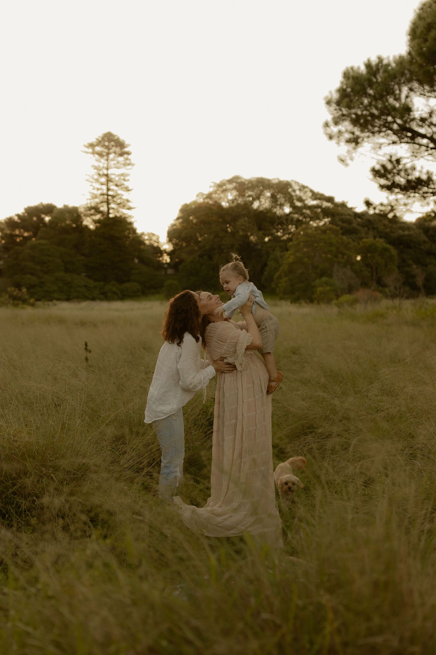 Intimate outdoor photoshoot in a golden field with white flowing dresses.