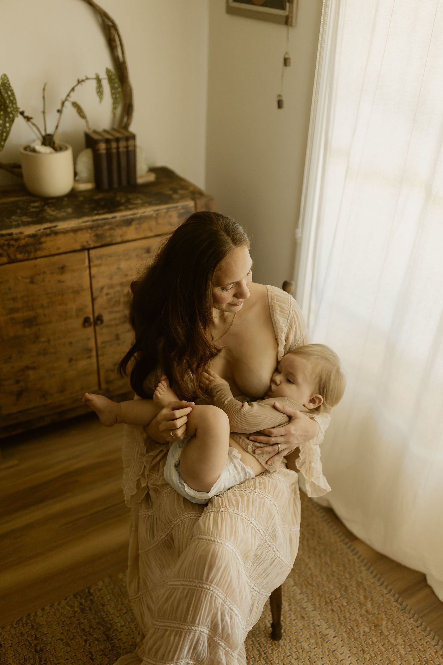 Lifestyle portrait session showing intimate parent-child bonding moment near window with natural light.