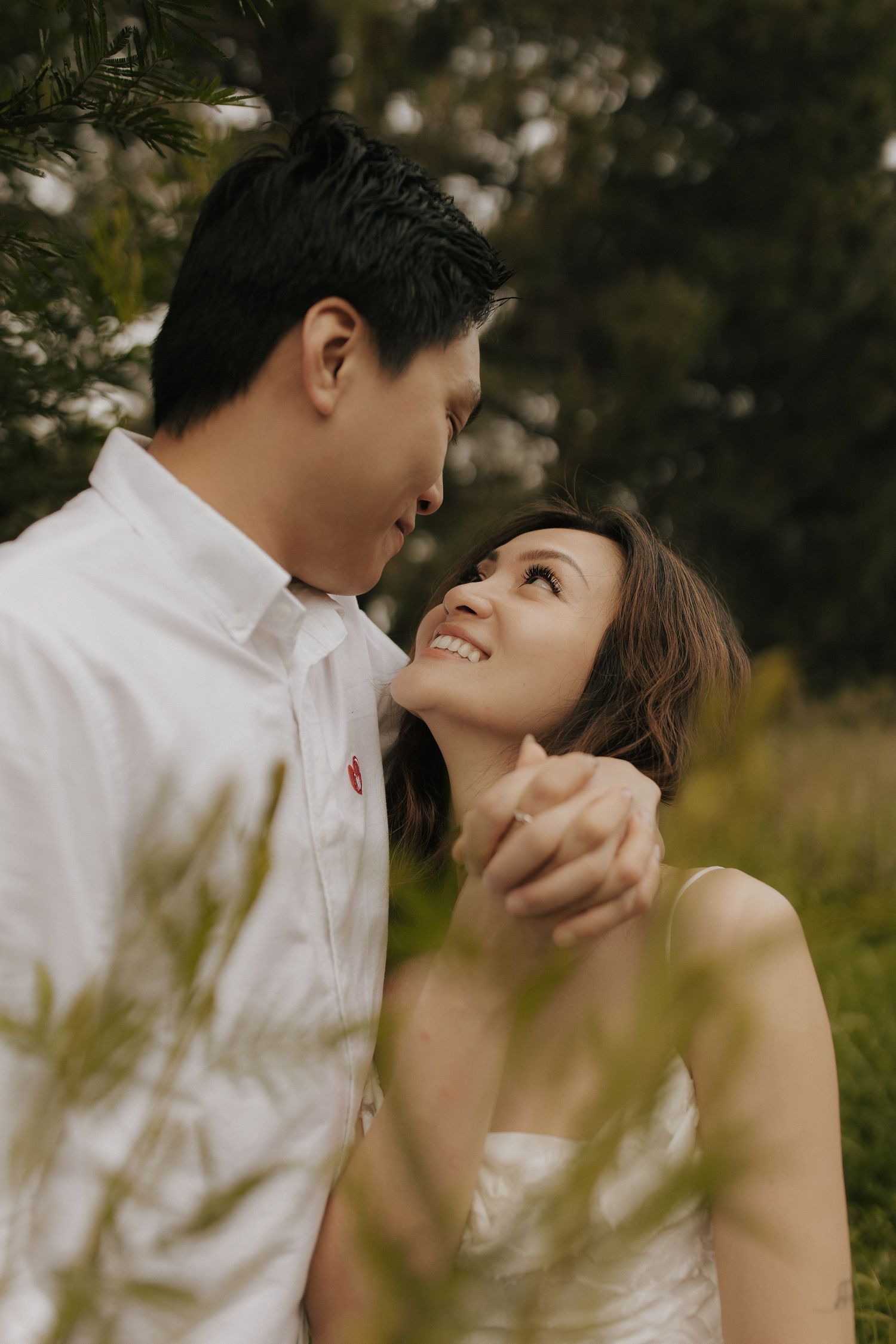 A romantic couple shares intimate moments in a natural outdoor setting with soft lighting and greenery.