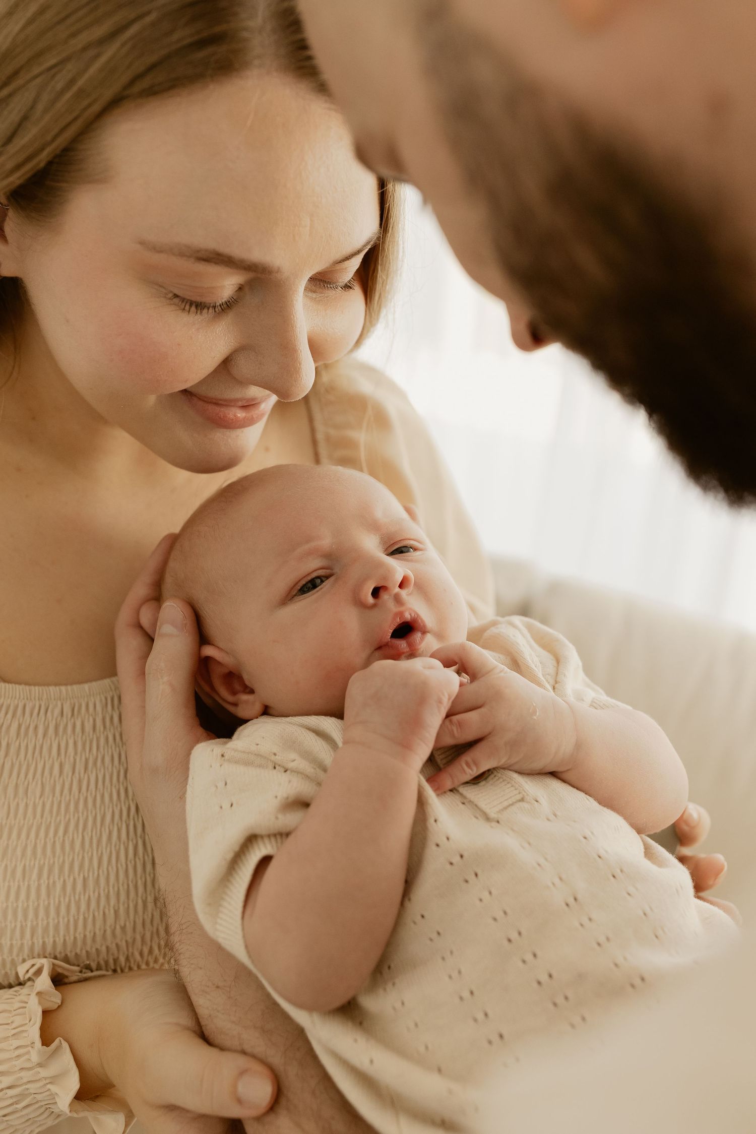 Warm candid photos show gentle moments of affection between family members and a small baby in soft lighting.