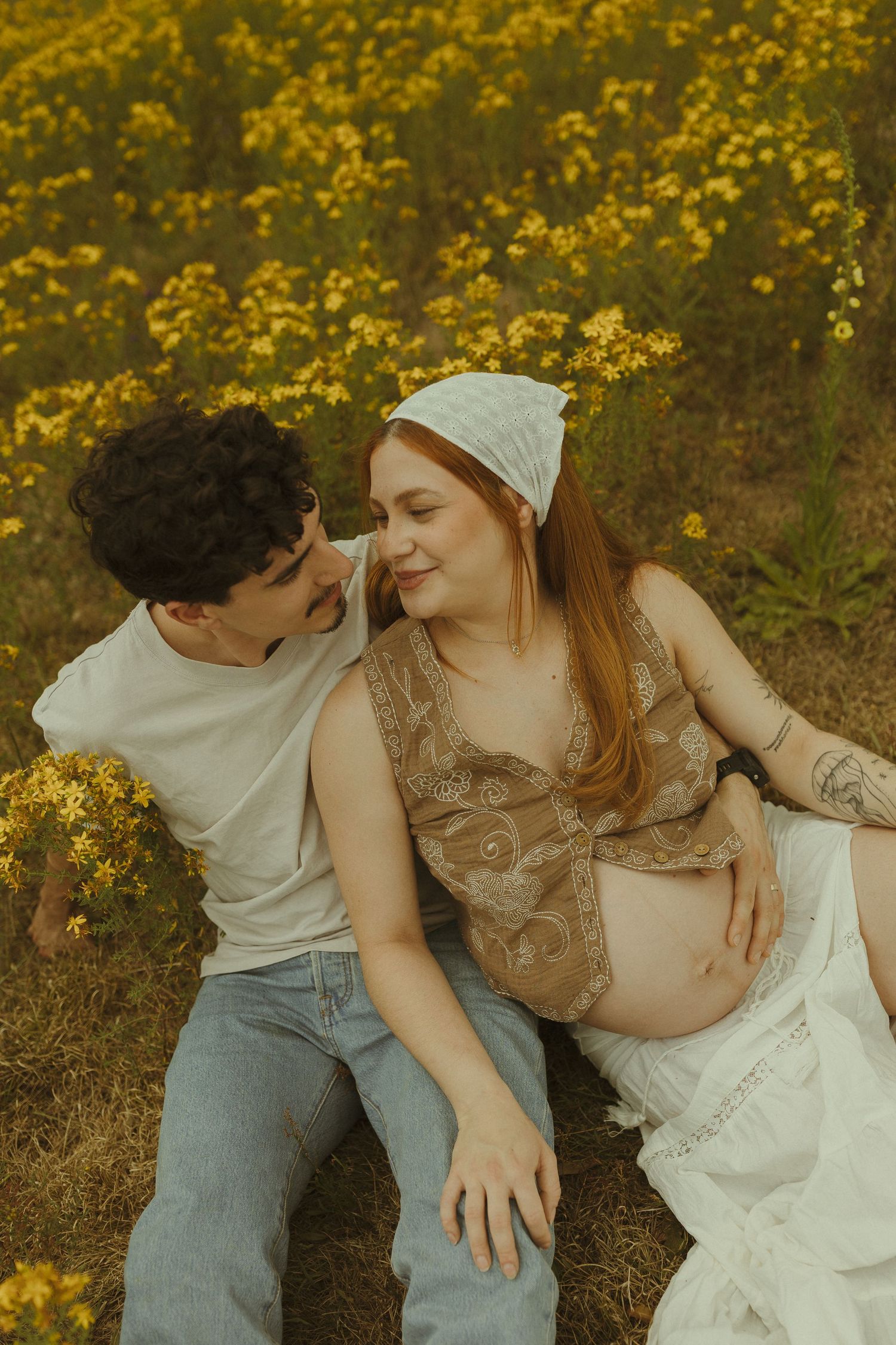 A romantic couple shares tender moments among blooming yellow wildflowers in a dreamy outdoor setting.