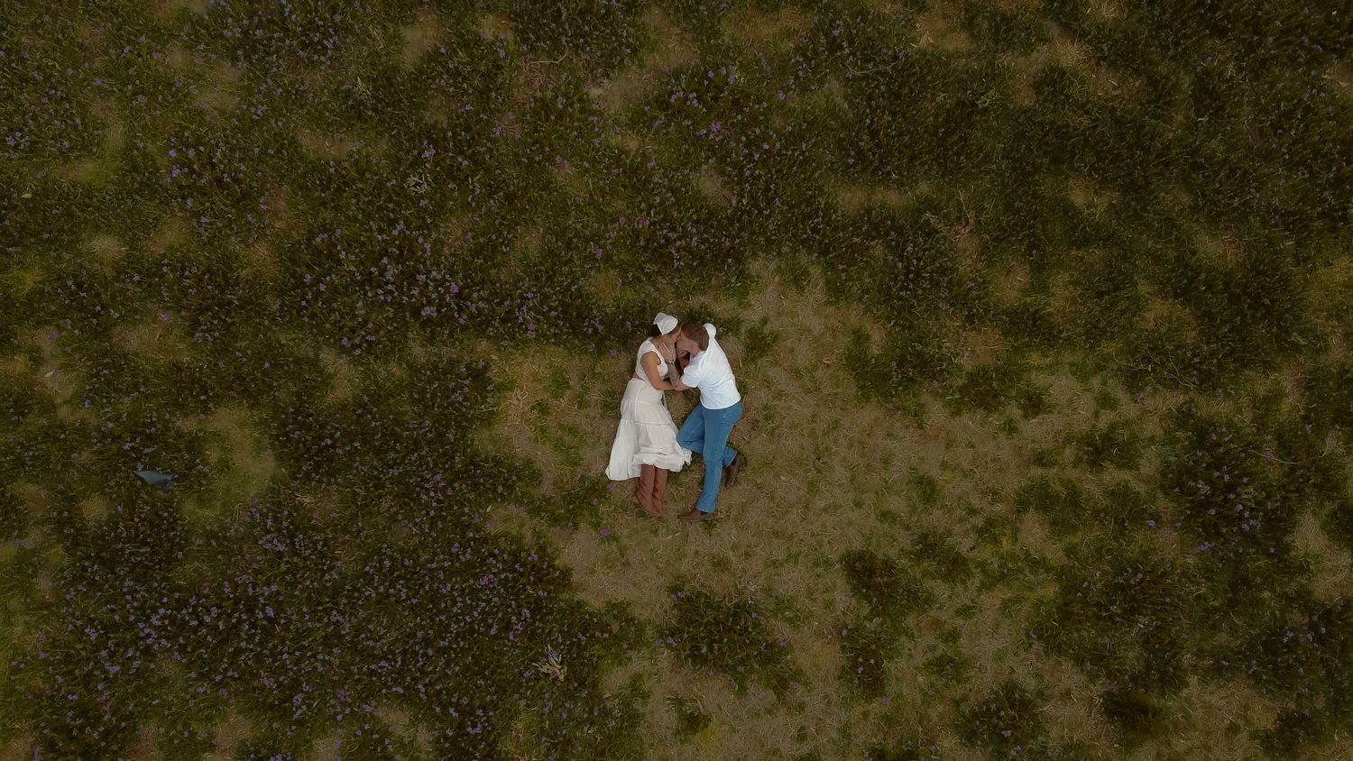 Couple embracing in a dimly lit natural outdoor setting.