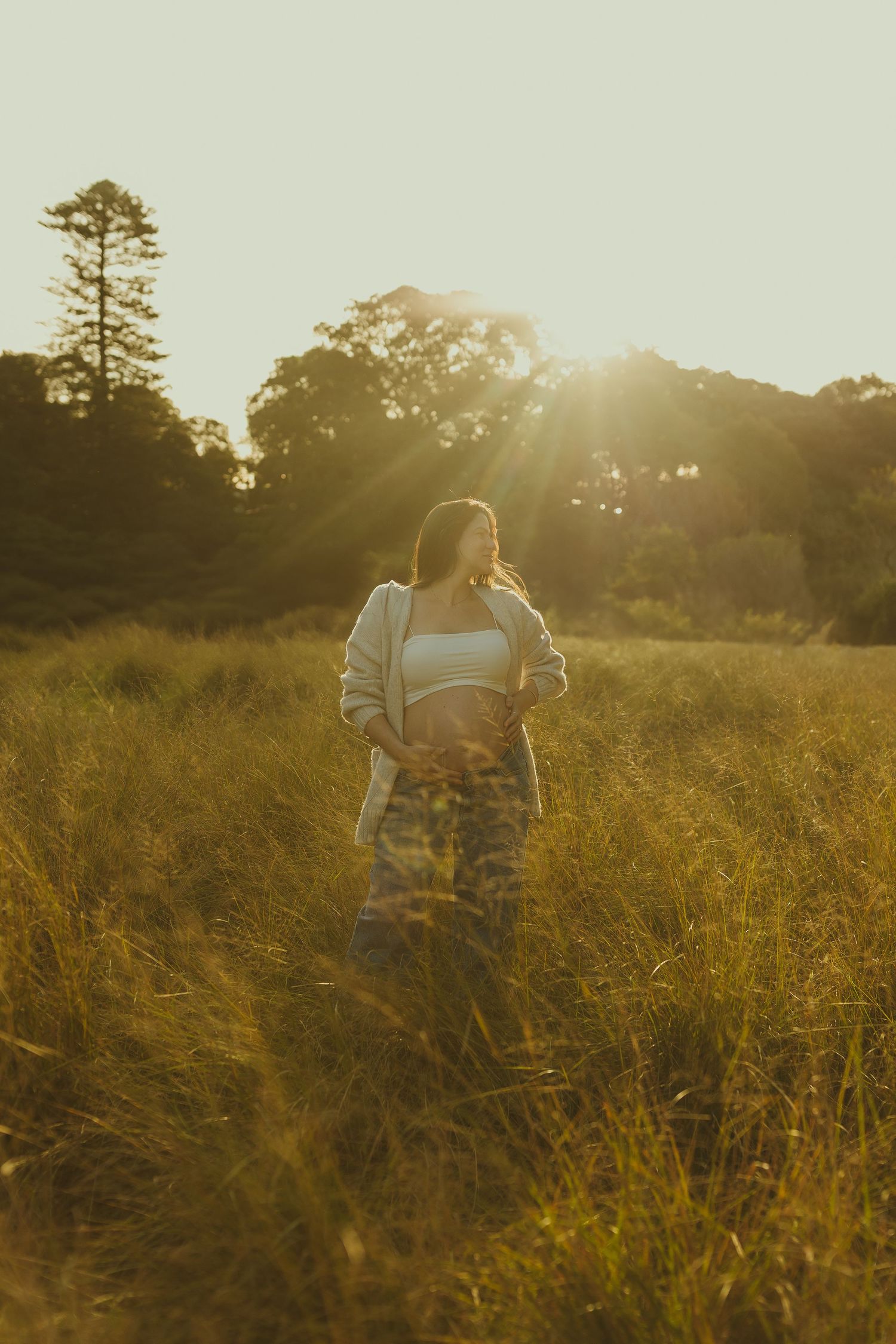Person walking through a sun-drenched field of tall golden grass at sunset.