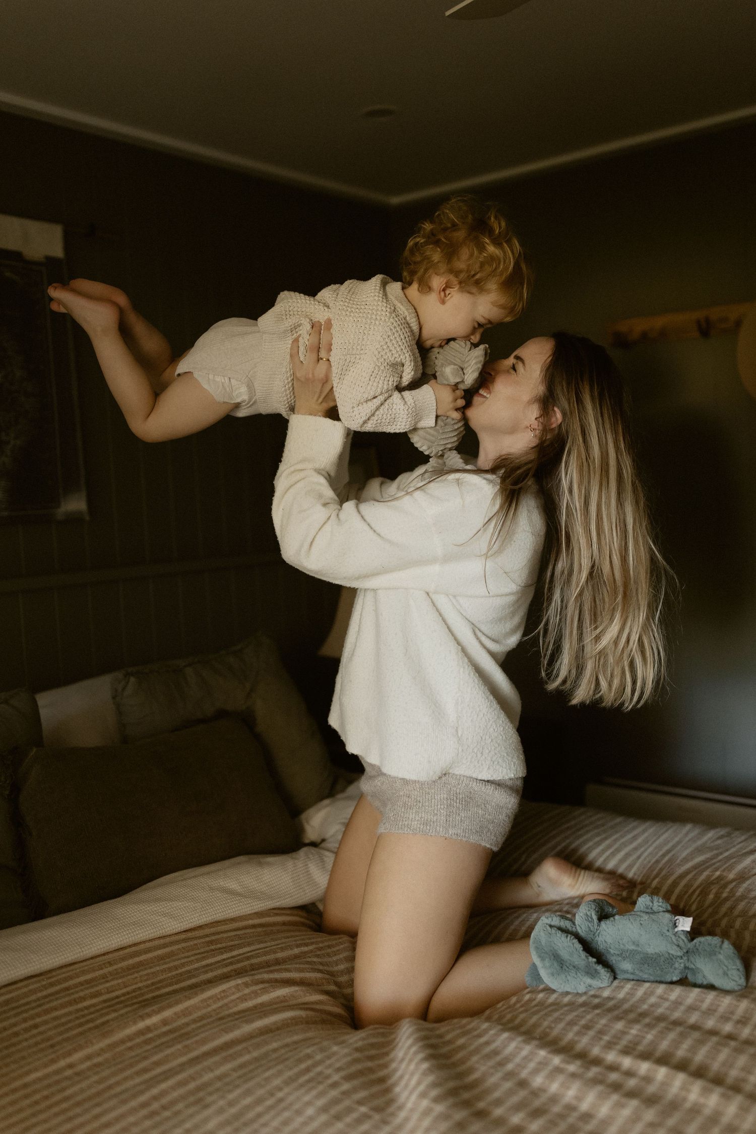 Intimate lifestyle photos of two people in white loungewear playing on a bed with romantic lighting.
