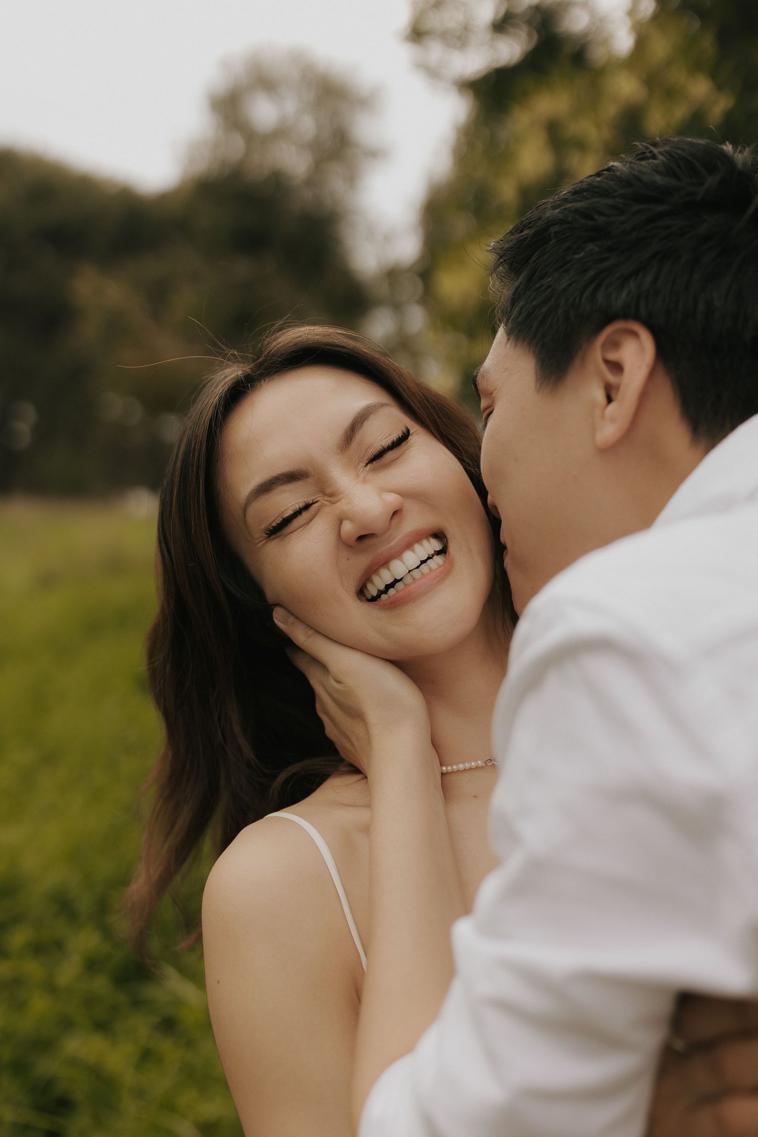A couple shares intimate romantic moments in a natural outdoor setting with warm lighting and greenery.