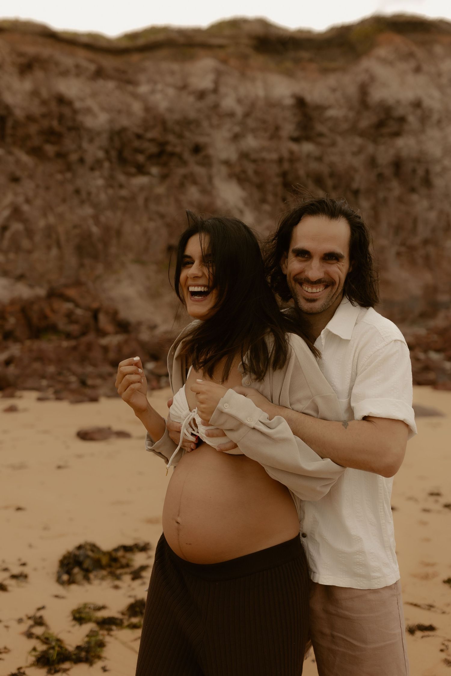 Joyful candid moment captured on sandy beach in sepia tones.