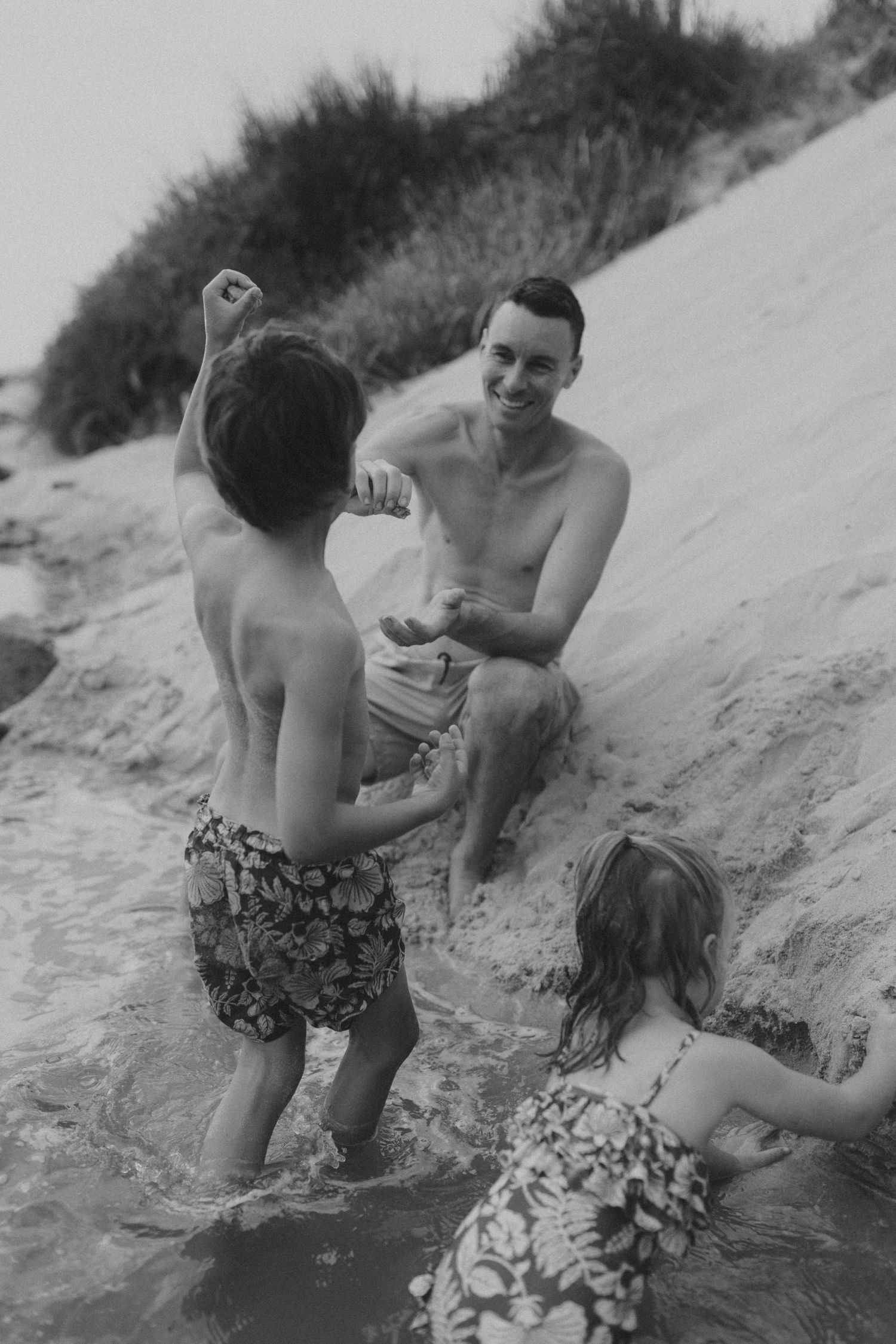 Sequence of black and white photos showing playful interaction at the water's edge.