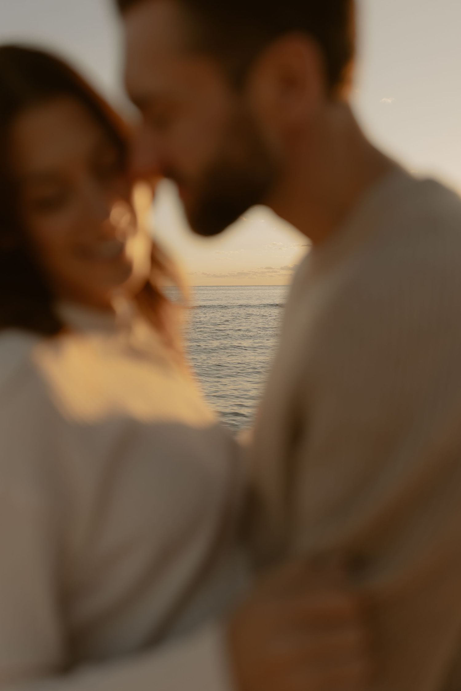 A couple shares an intimate moment at sunset by the ocean.