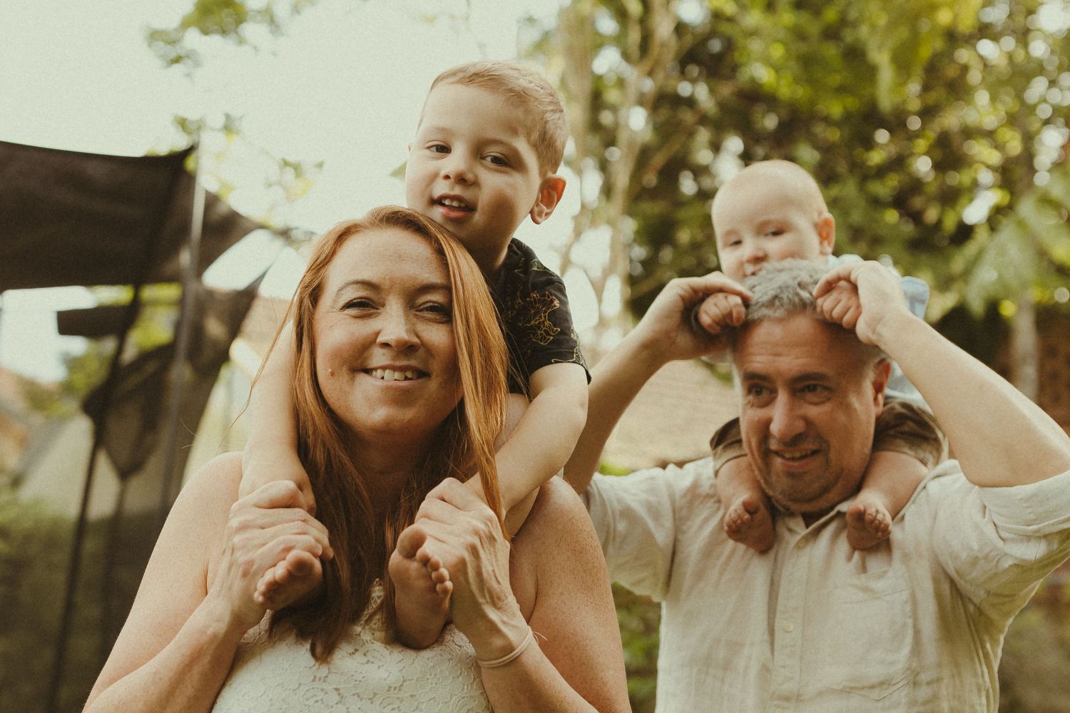 Joyful family interaction captured in warm sunlight against garden backdrop.