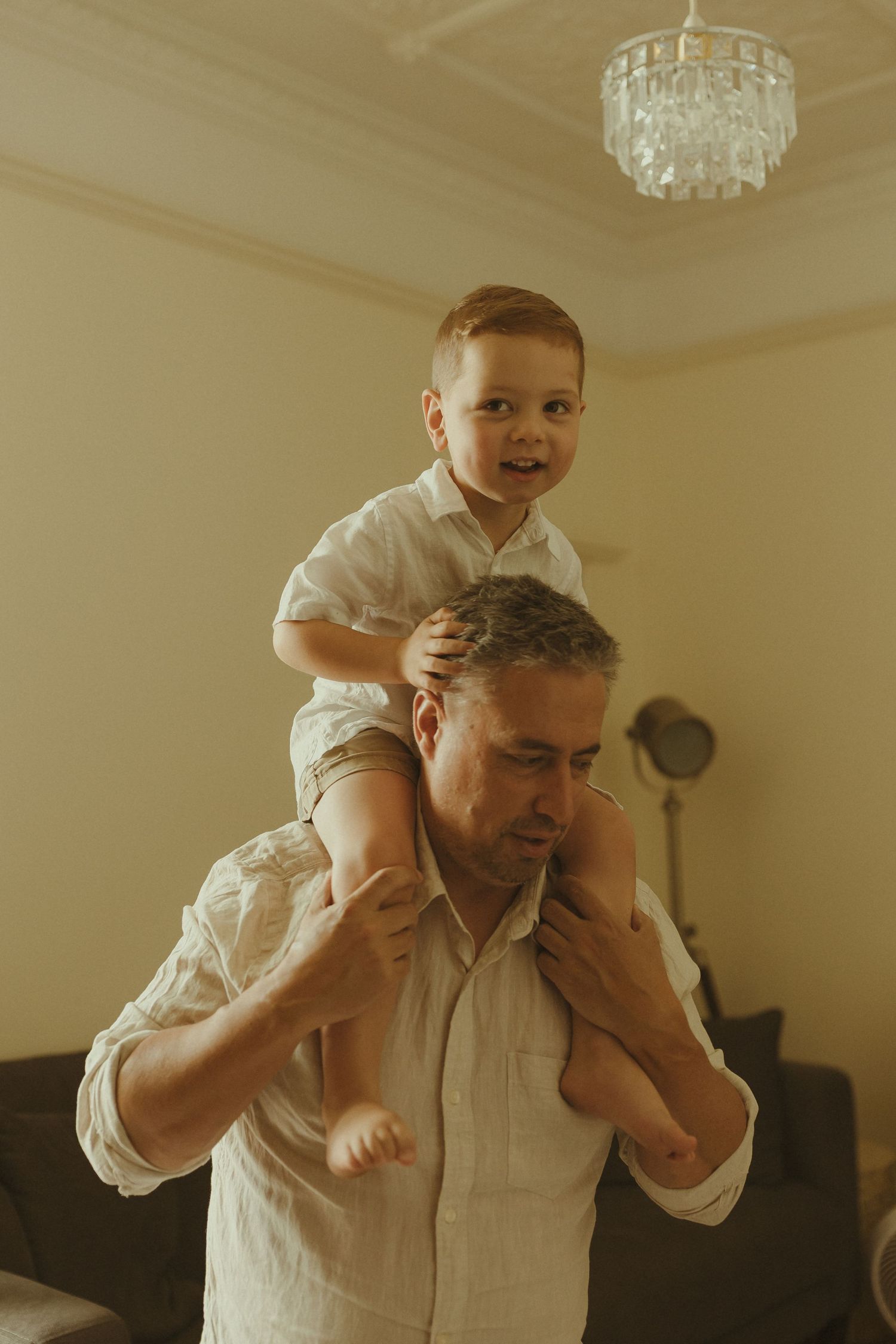 A heartwarming sequence shows a playful shoulder ride moment between parent and child in a sunlit room.