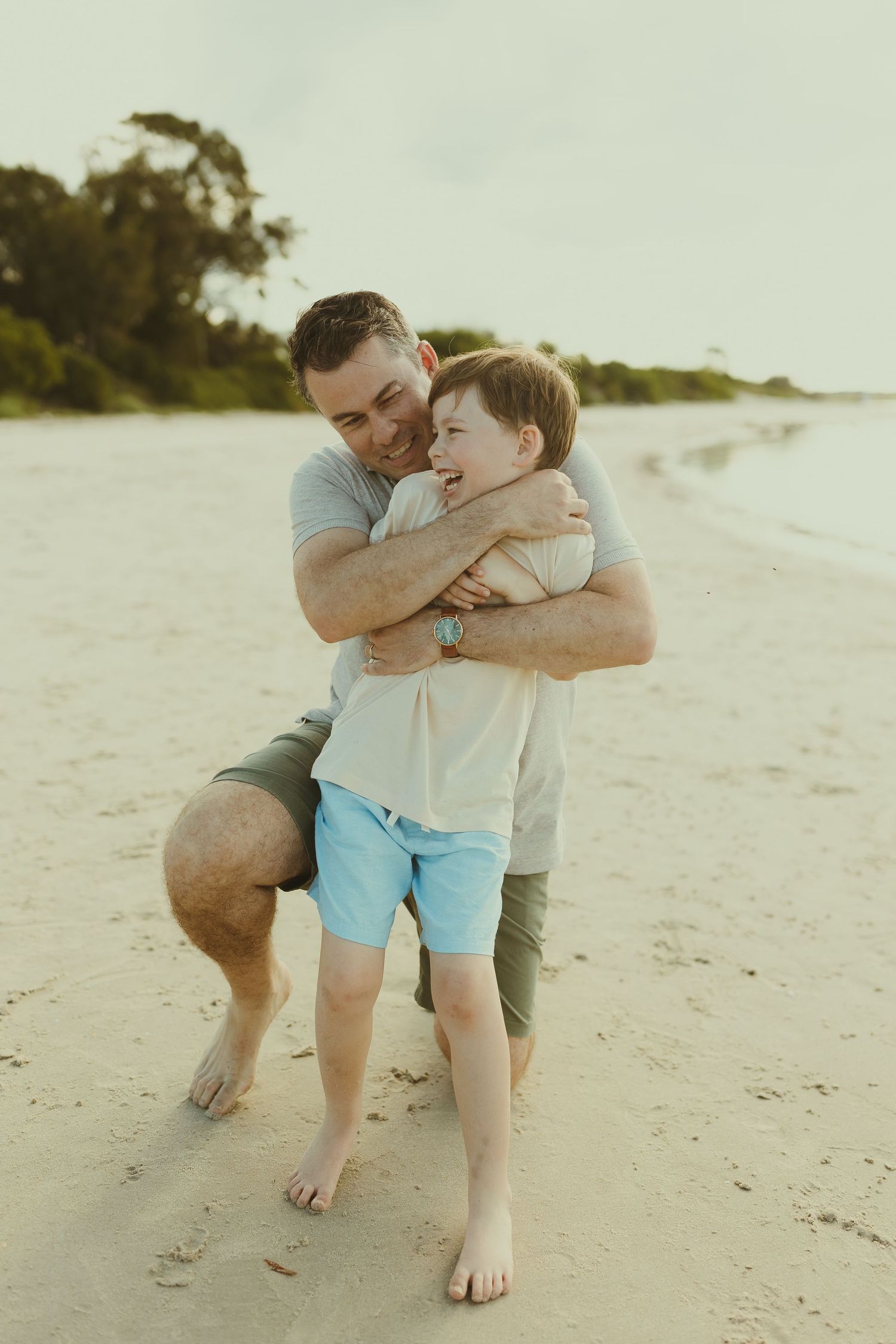 A touching moment between parent and child playing together on a sunny beach at sunset.