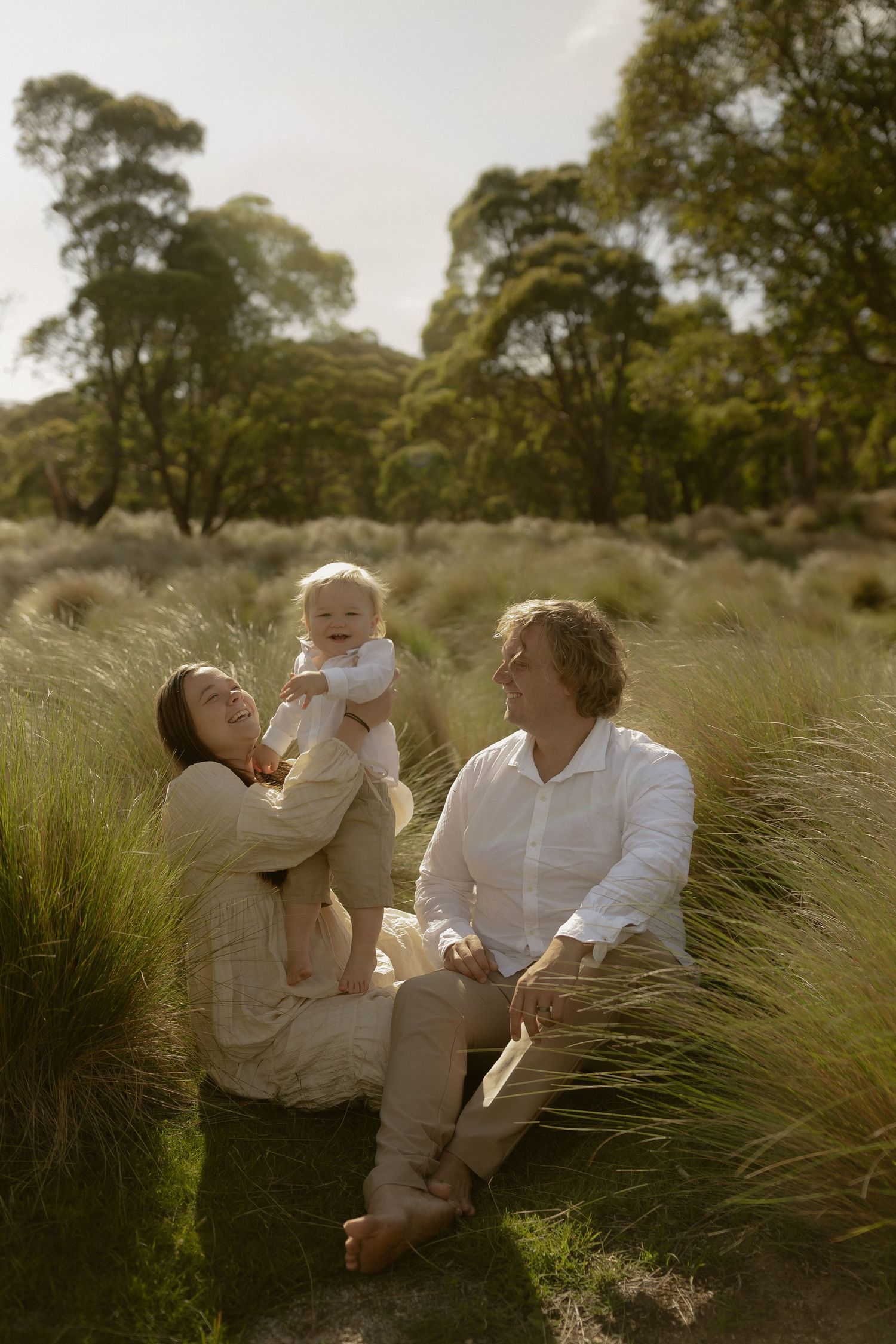 Candid family interactions and laughter while sitting together in a natural grass field setting.