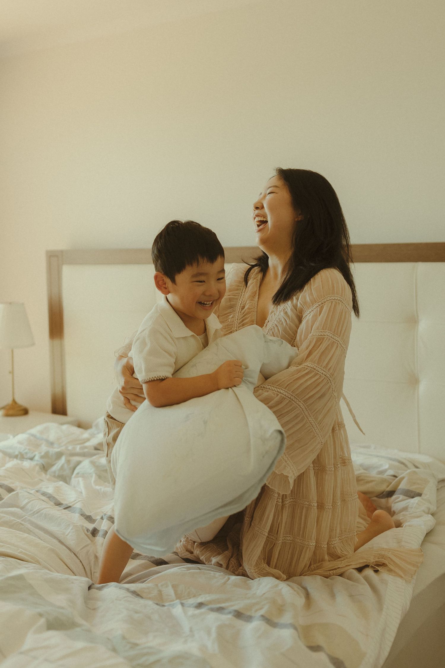 Joyful laughter fills the room as people play with pillows on a cozy bed.