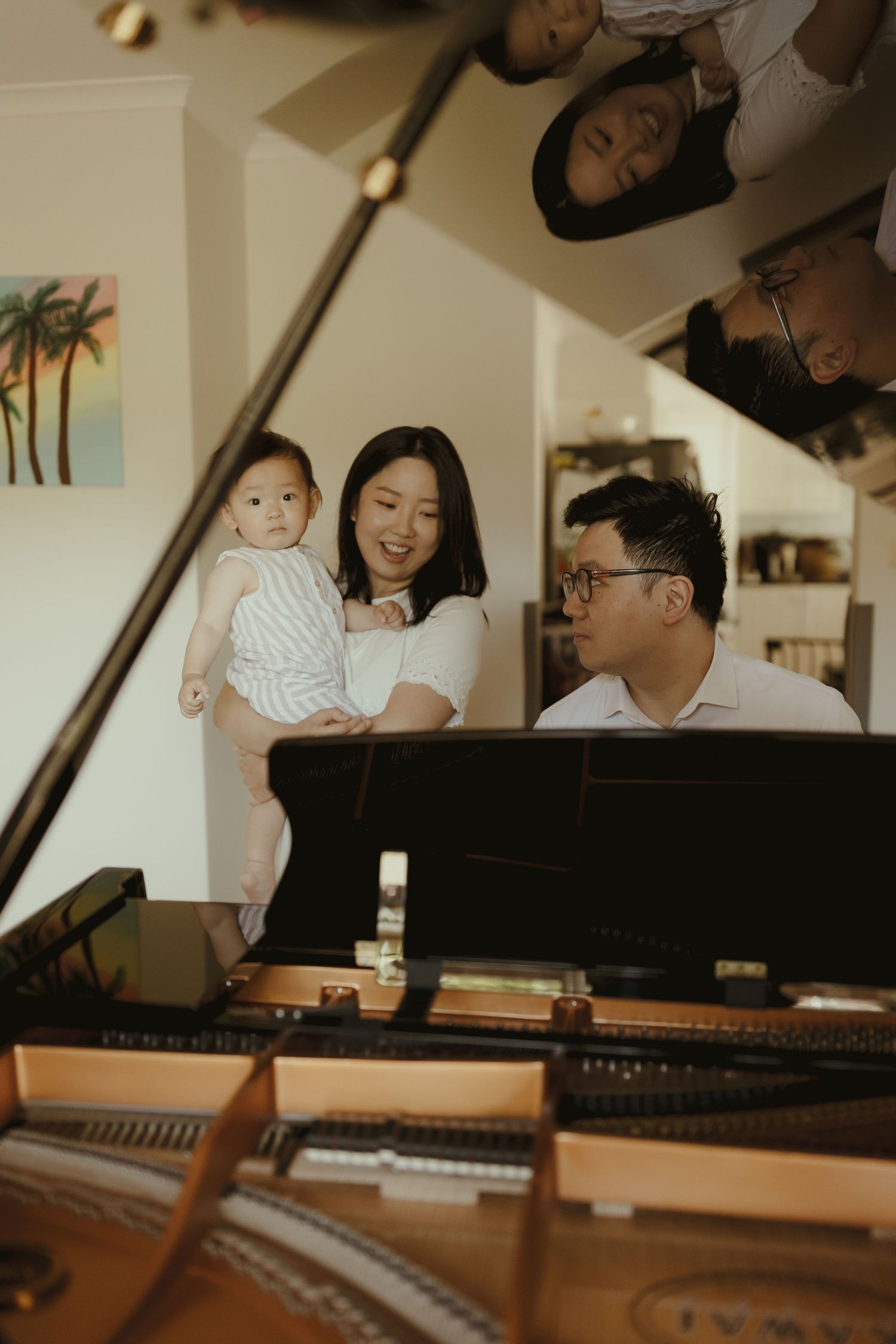 A family shares tender moments around a piano in a warmly lit room.