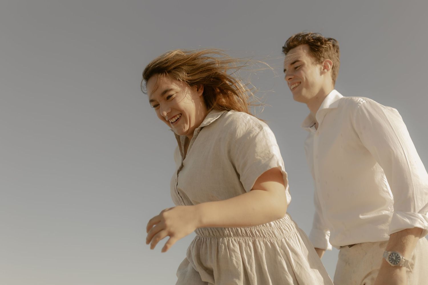 Couple embracing and dancing together on a beach at sunset.