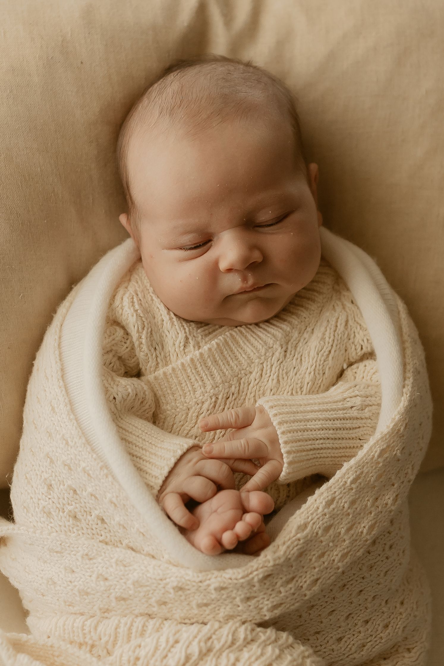Sleeping newborn wrapped snugly in cream-colored knit blanket shown in artistic progression photos.
