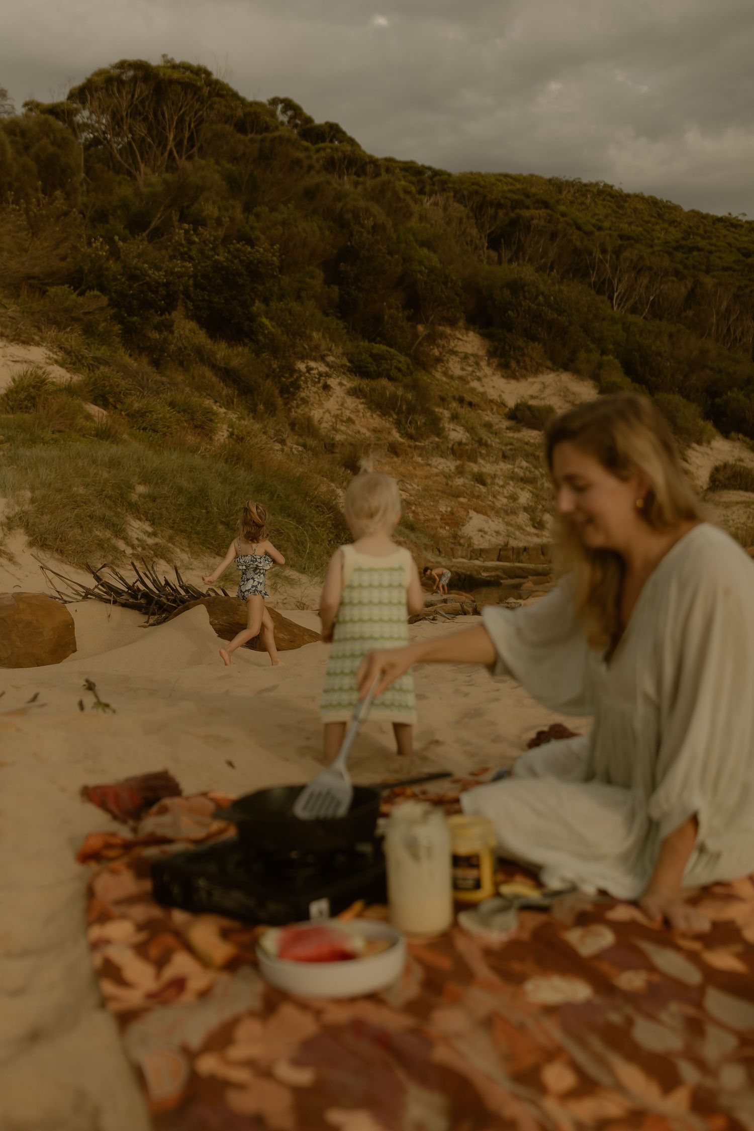 A picnic setup on a sandy beach with rocky cliffs in the background.