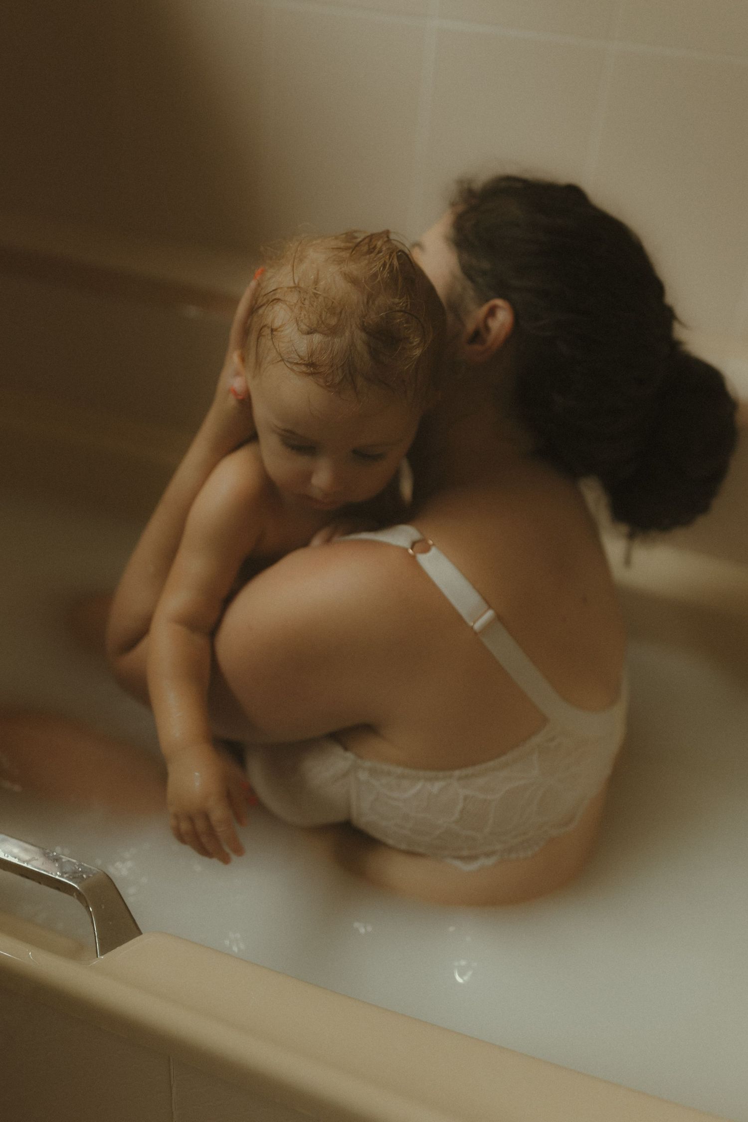 Dreamy bathroom photography shows a quiet moment of connection between parent and child.