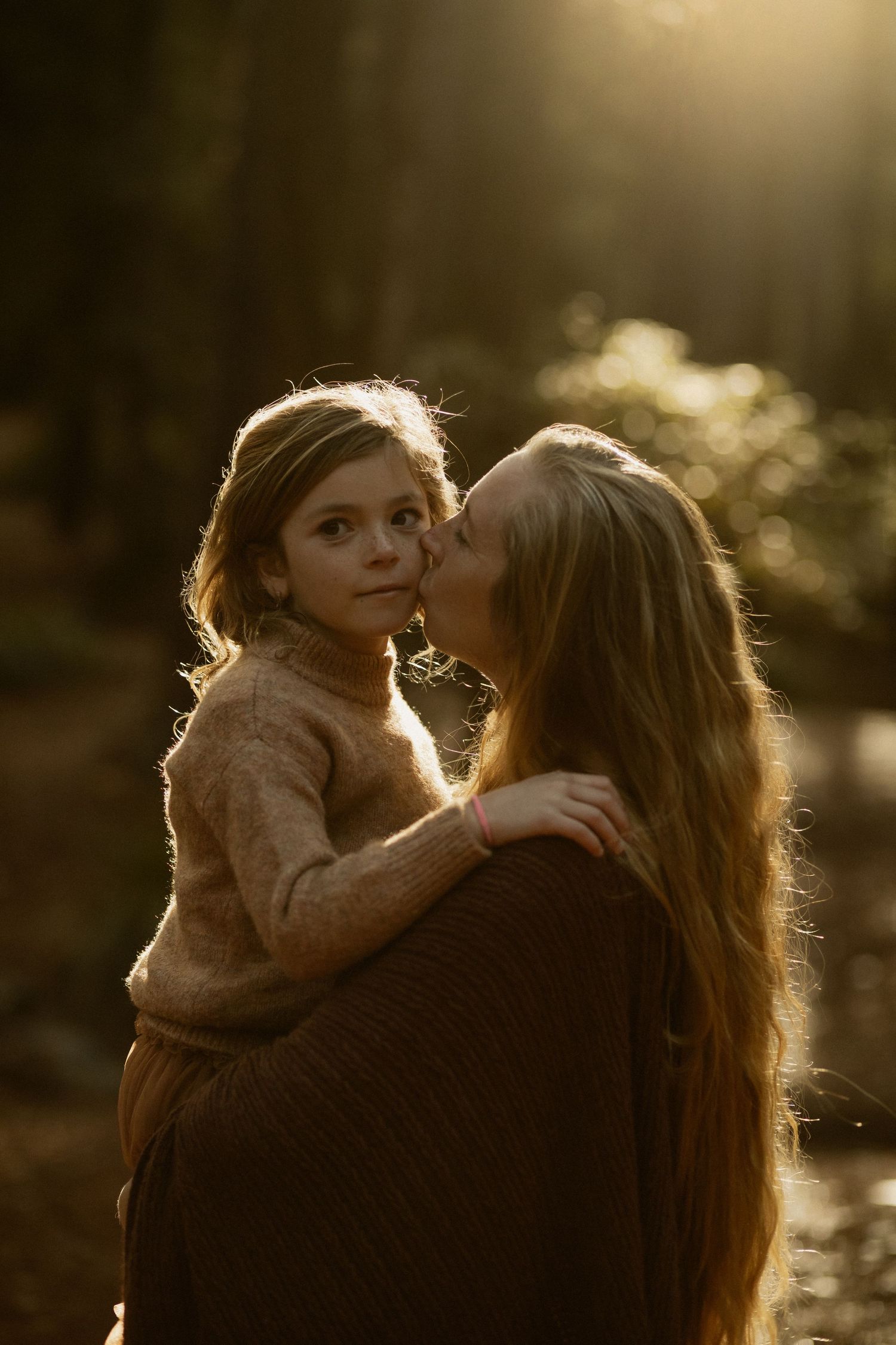 A tender embrace captured in golden sunlight filtering through a forest grove.