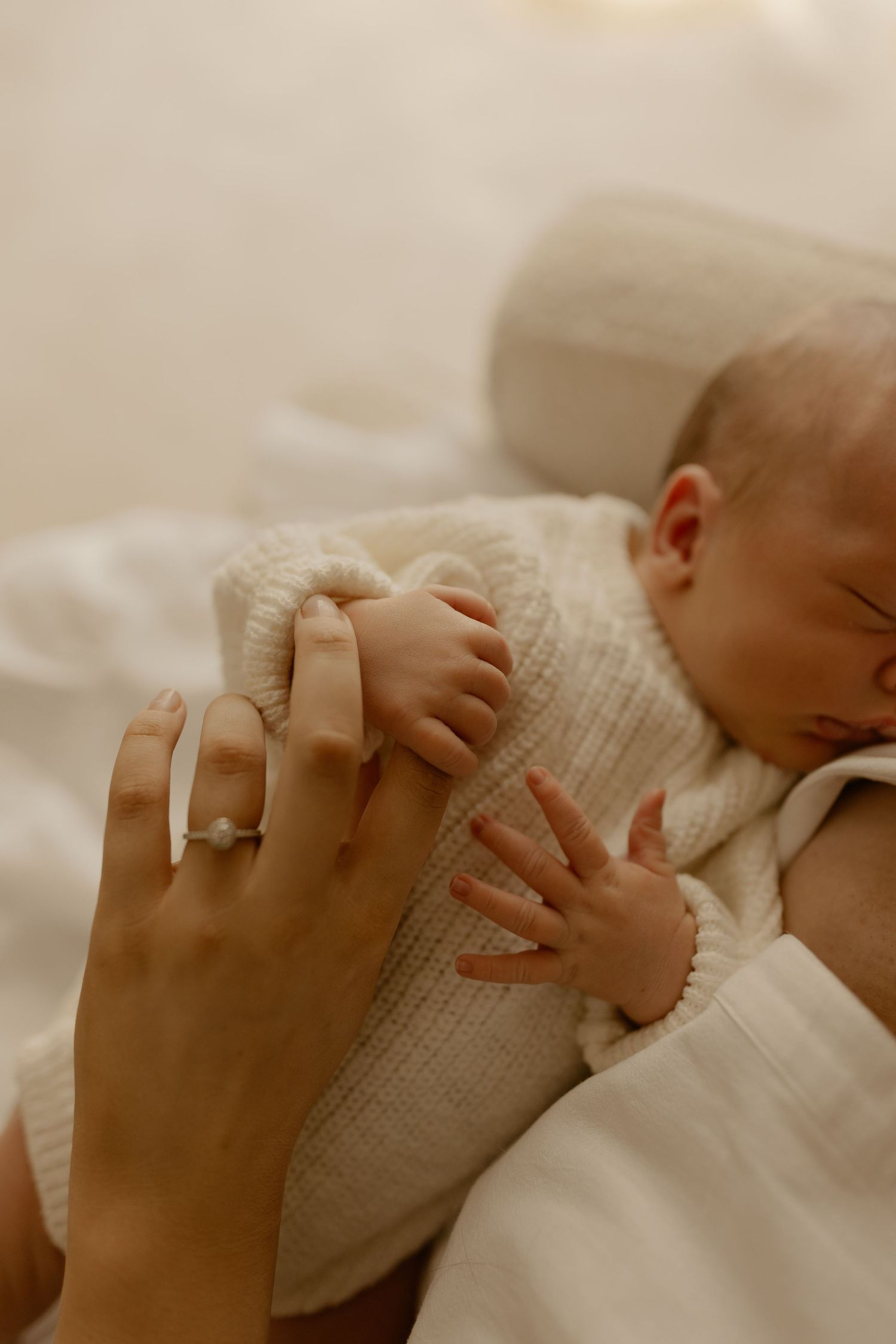 Close-up sequence of a newborn baby's tiny hand grasping against a soft white blanket in warm sepia tones.